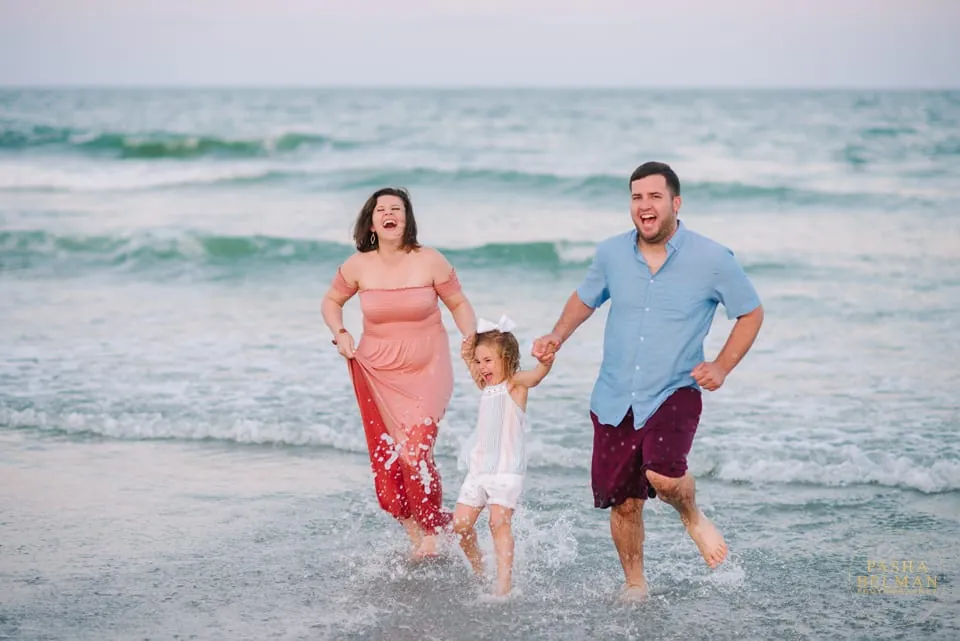 Family portrait as warm sunset colors fill the sky over the water