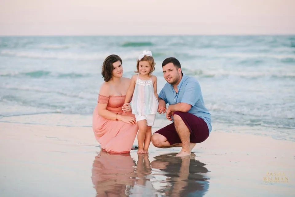 Family portrait with the uncrowded beach stretching behind them