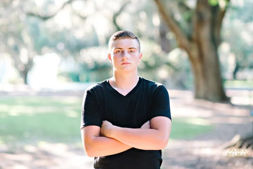 Senior picture for a guy leaning against a Spanish moss draped tree near Myrtle Beach