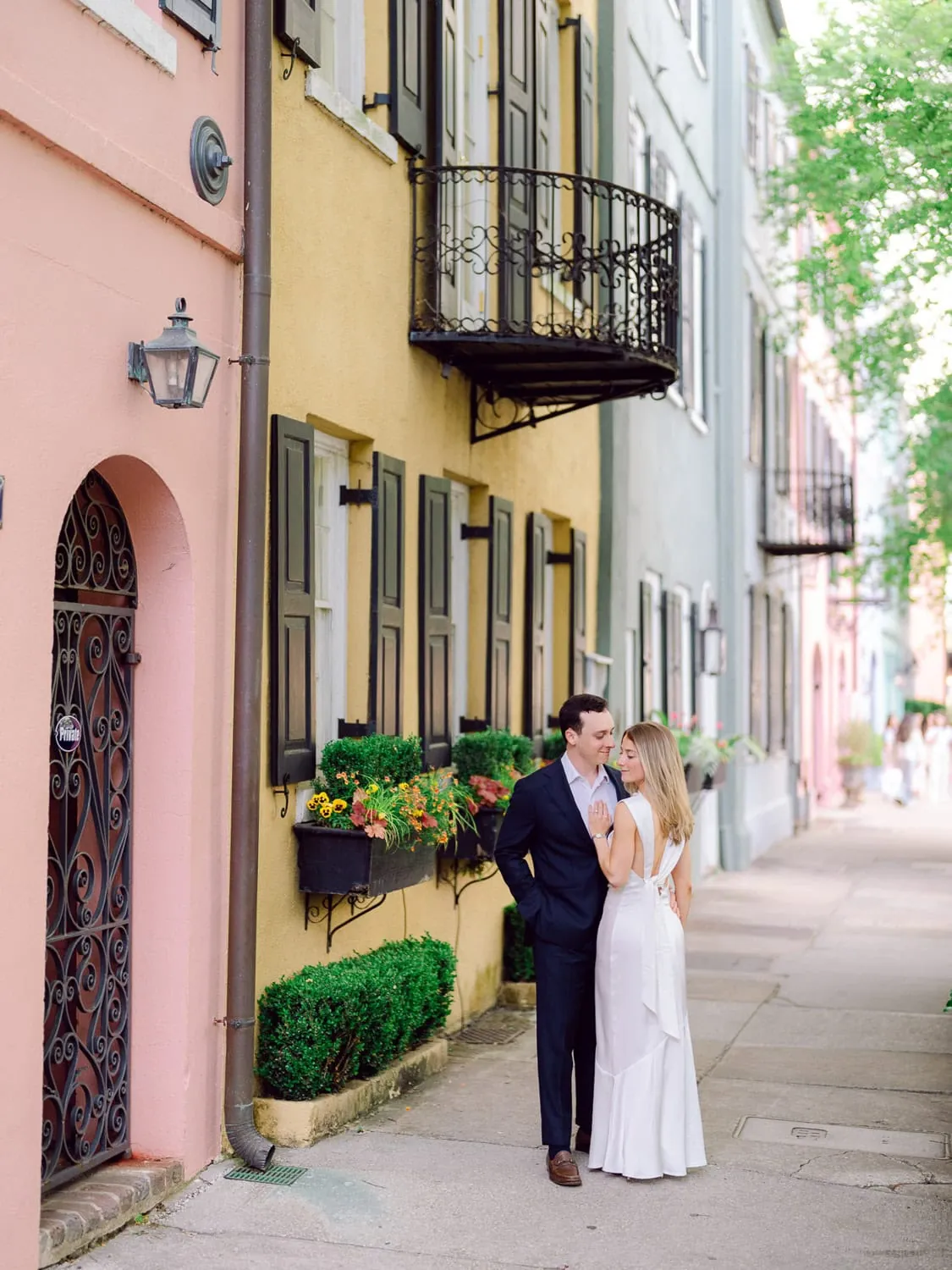 Engagement couple walking beside colorful Charleston homes
