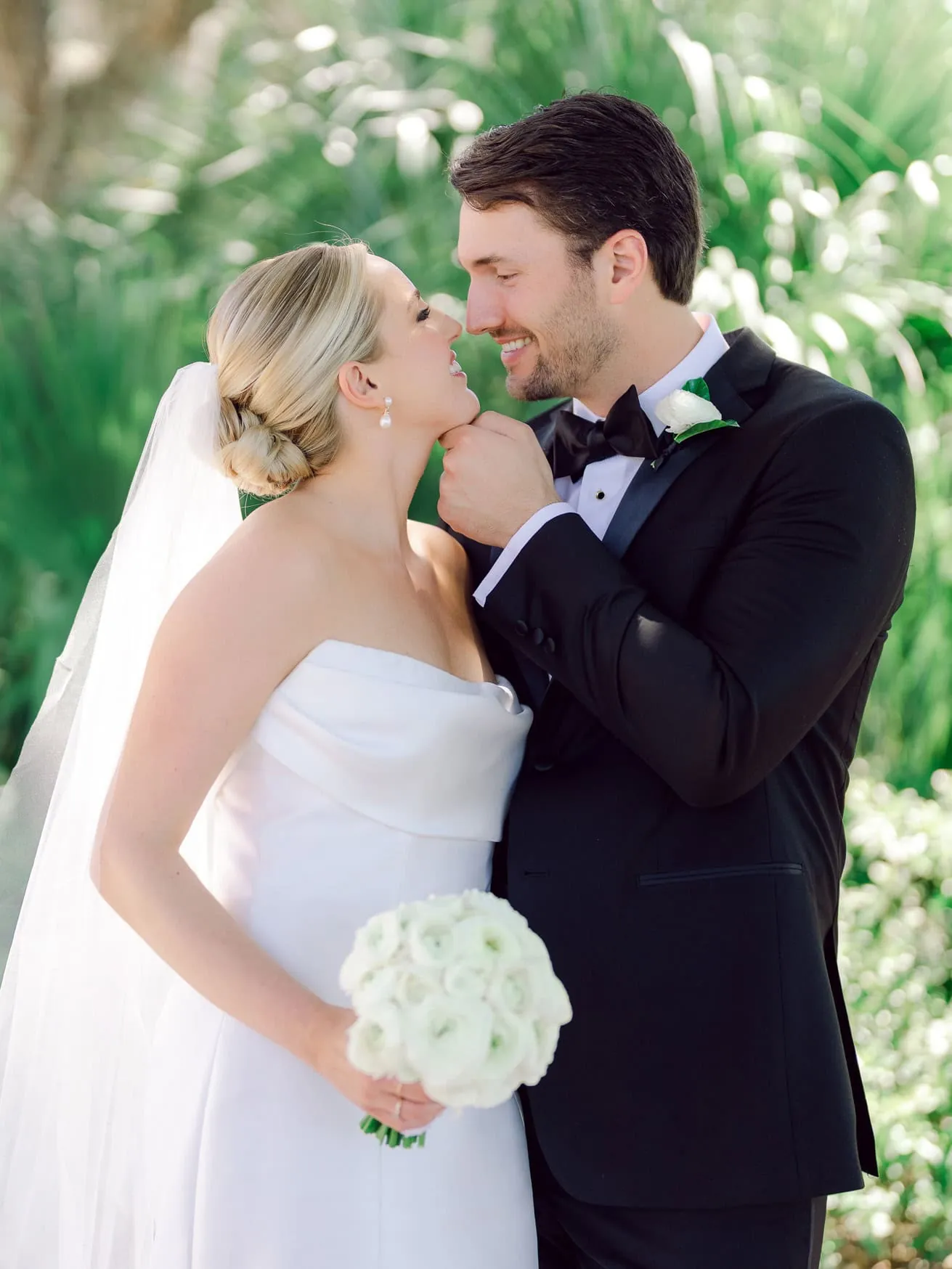 Close-up of bride and groom sharing a tender moment during their wedding portrait, with greenery in the background, highlighting elegant wedding photography.