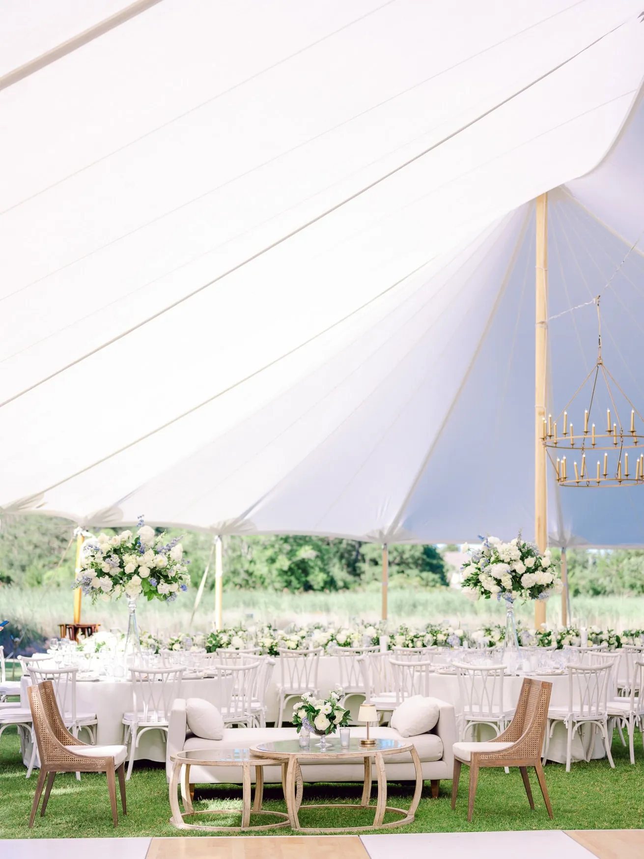 Elegant outdoor wedding reception under a white tent with floral centerpieces, rustic furniture, and romantic lighting, perfect for summer wedding photography and family celebration portraits.