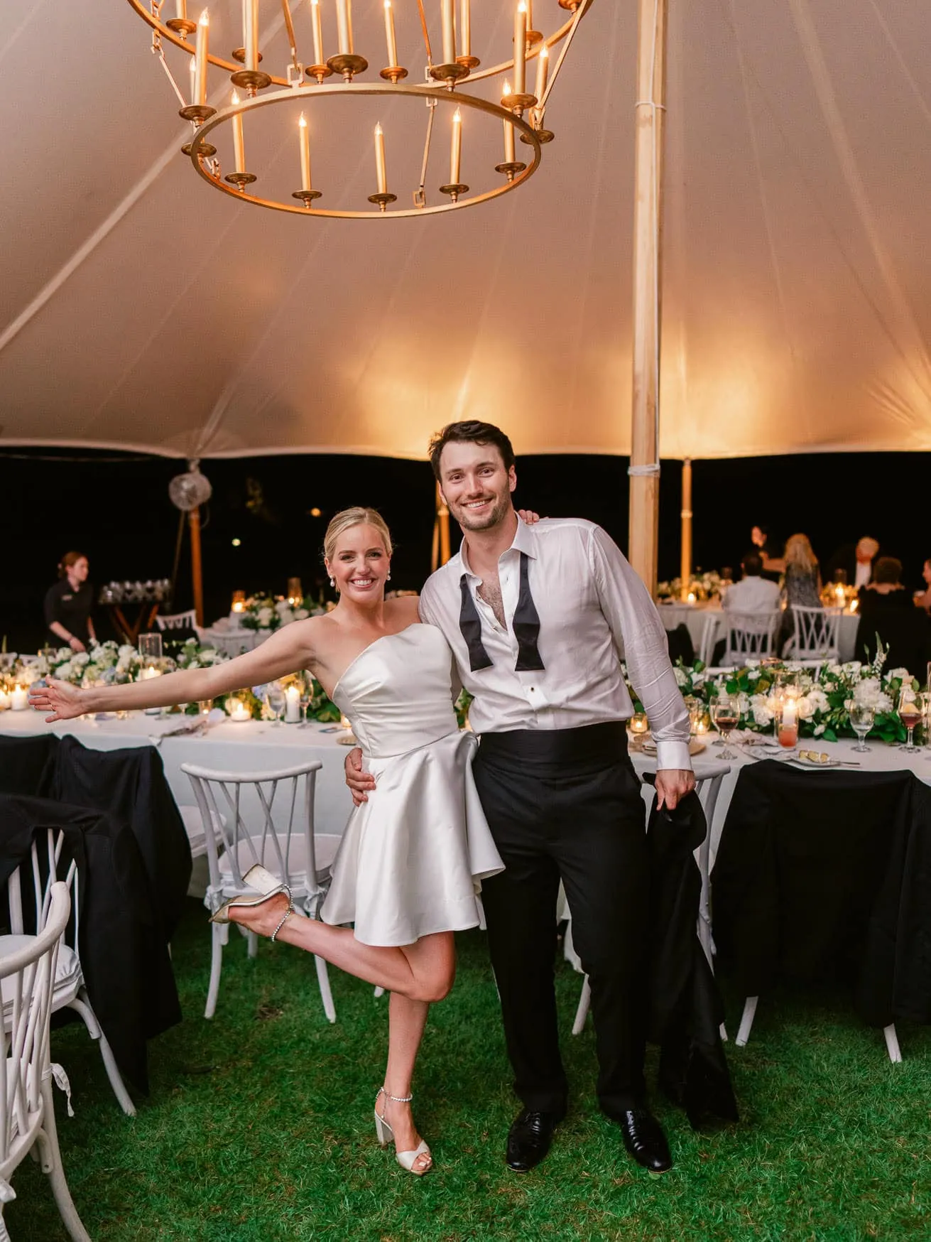 Vibrant wedding reception under a large tent with elegant table settings and romantic lighting, featuring joyful newlyweds celebrating their special day.