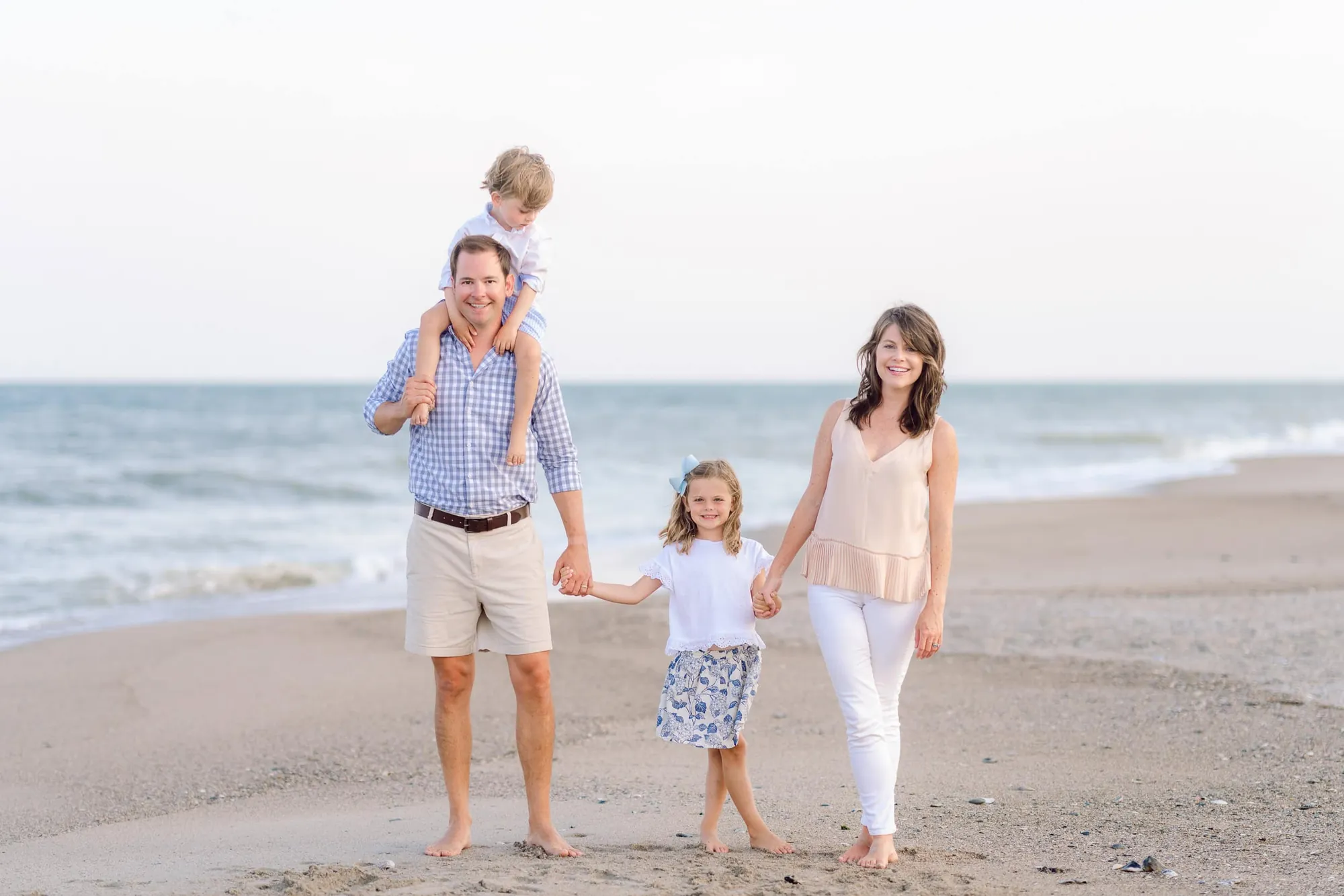 Relaxed beach family portraits showing coordinated outfits and natural interaction