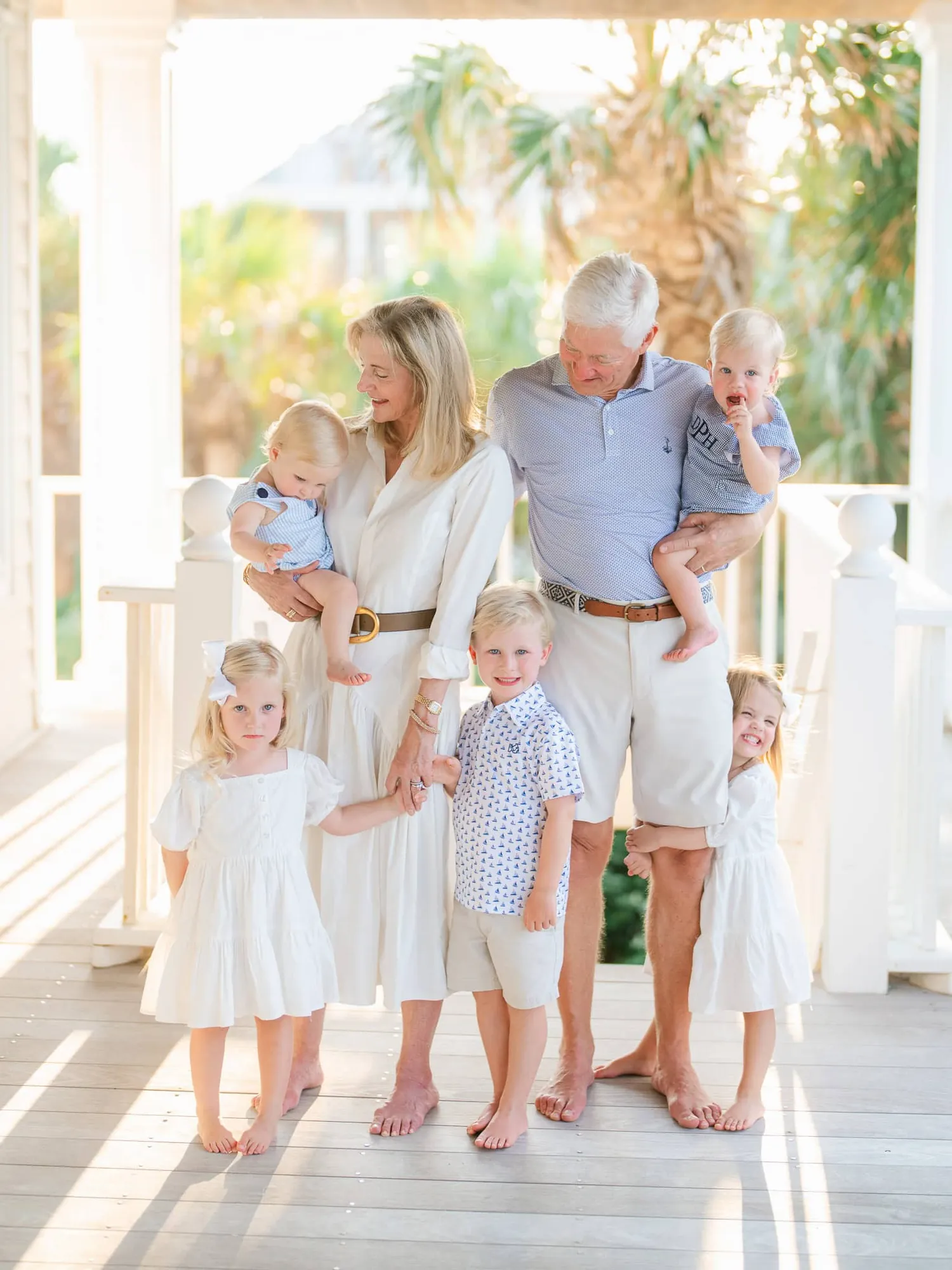 Family posed on porch of beach rental house with natural framing and ocean view
