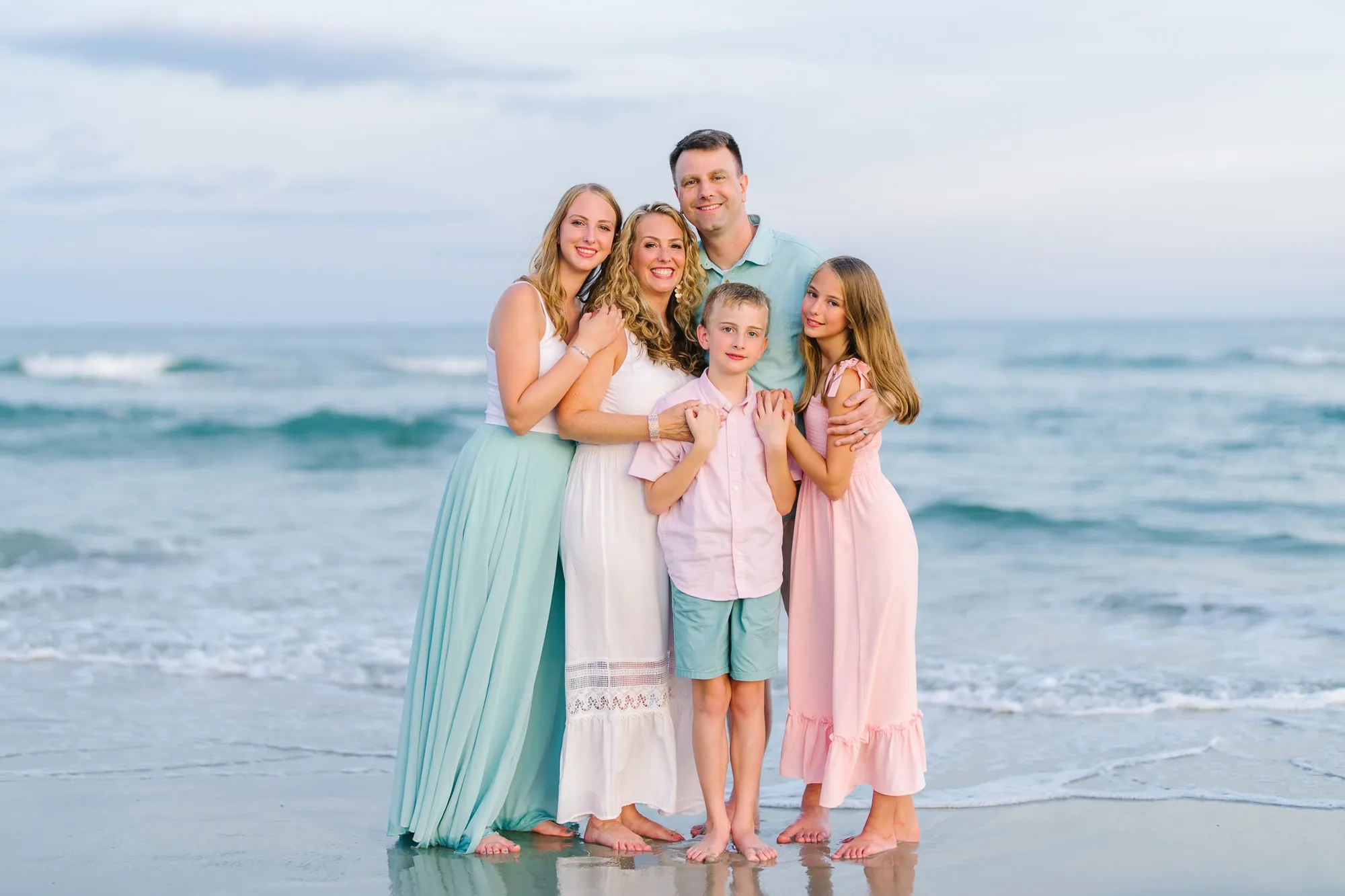 Parents and children laughing together during sunset beach portraits