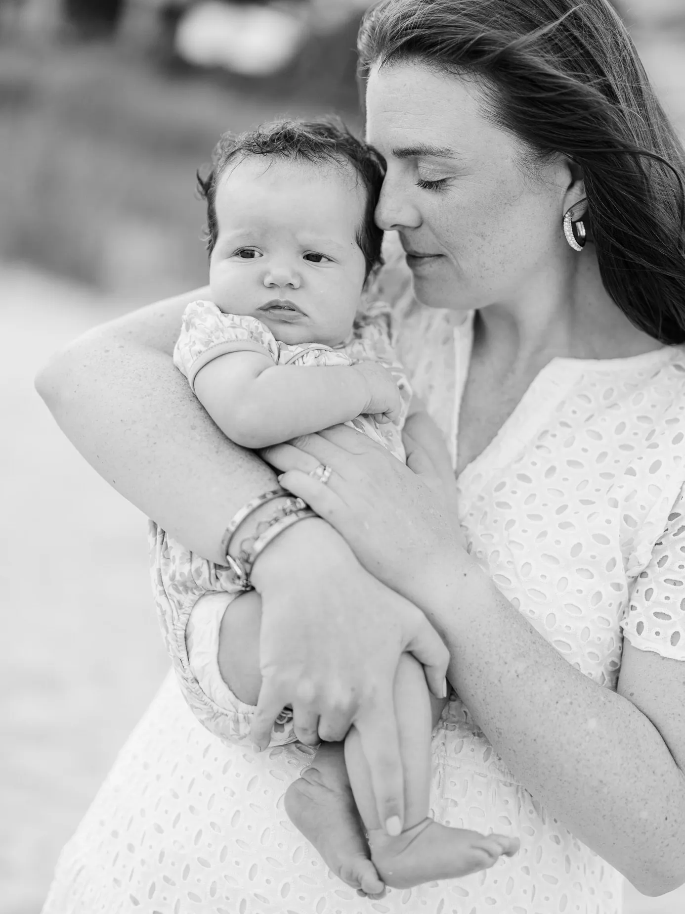 Mother holding her young child during a quiet moment at their family beach session