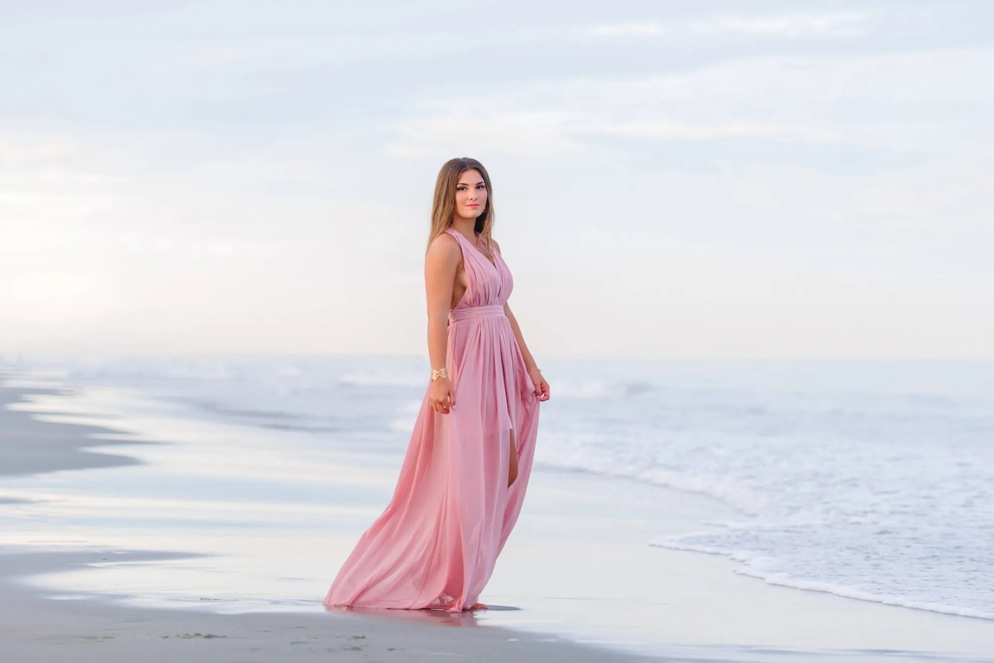 High school senior photos on the beach with soft pastel sunset tones