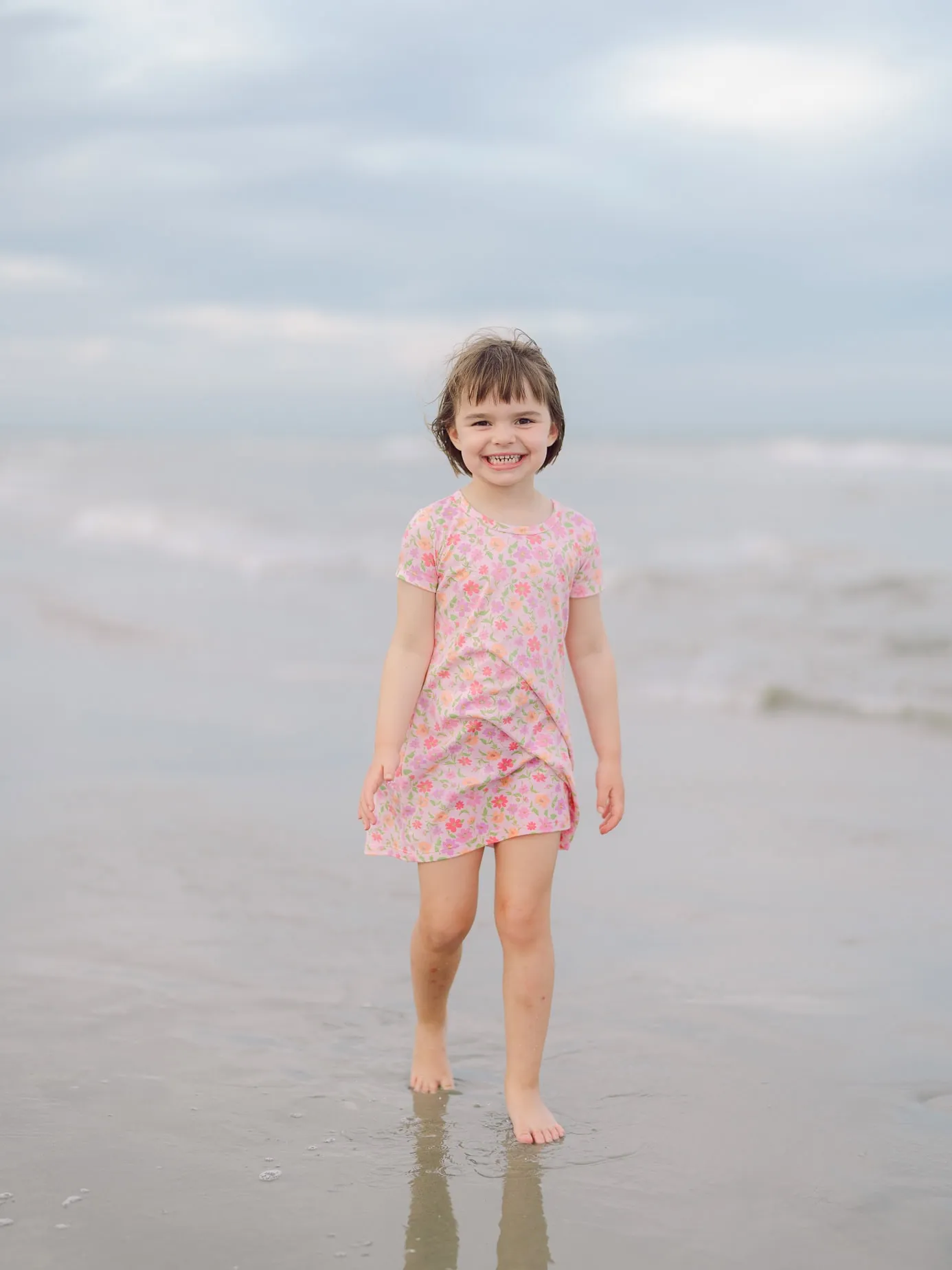 Young girl walking barefoot near the ocean during her family's Myrtle Beach portrait session