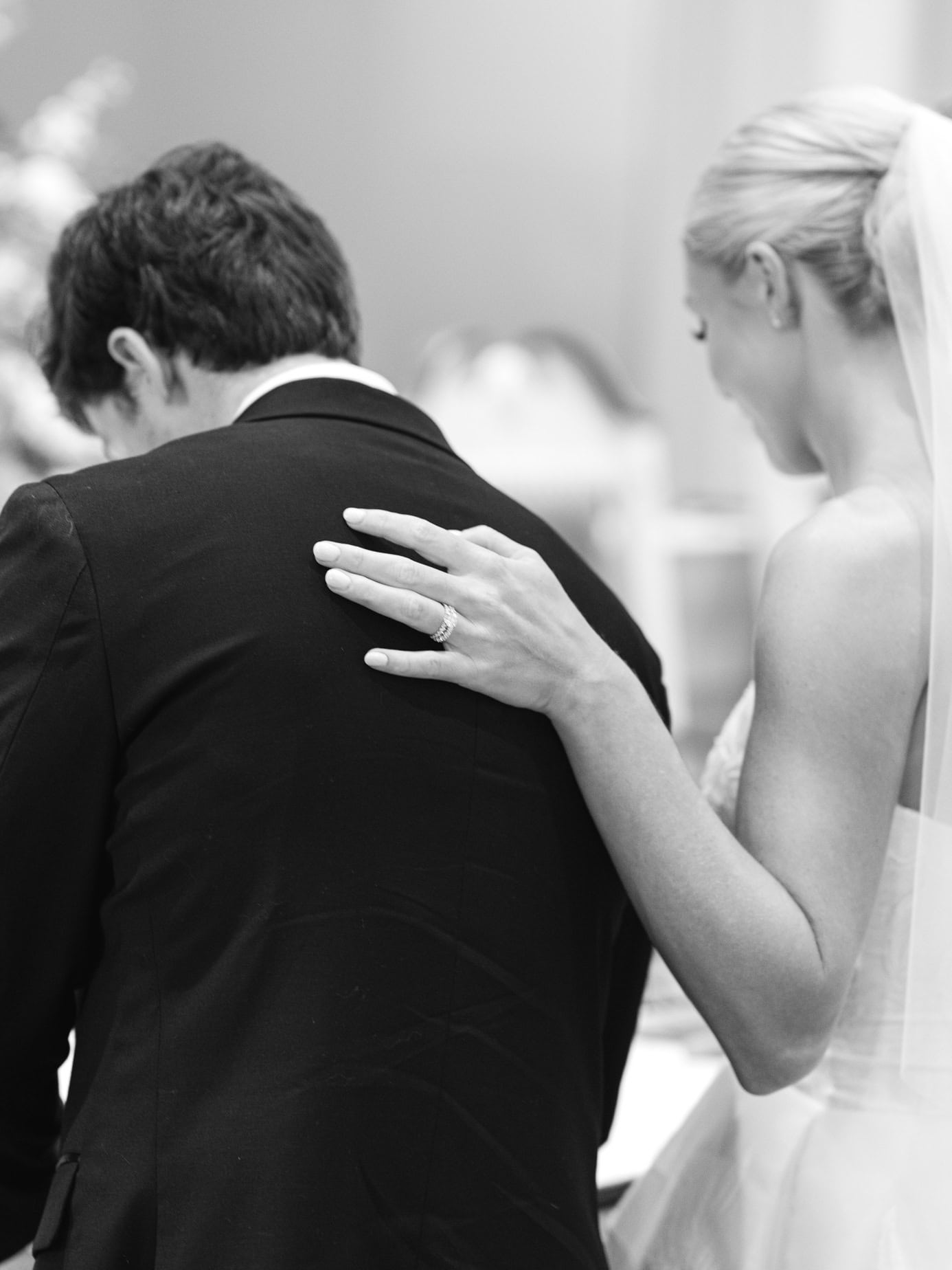 Close-up of a bride gently touching her groom during a wedding ceremony, showcasing intimate moments and emotional connection, black and white wedding photography emphasizing love and sentiment.