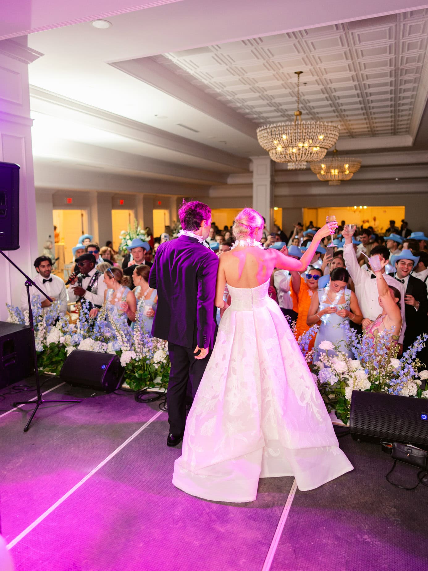 Elegant wedding reception with bride and groom dancing surrounded by guests in formal attire at a luxurious indoor venue.