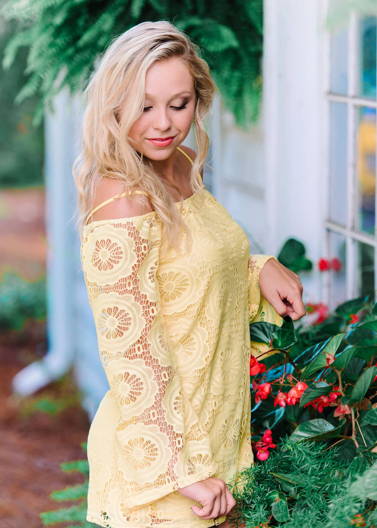 Vibrant portrait of a young woman in a yellow lace dress at a botanical garden, showcasing professional lifestyle photography with natural lighting and green foliage background.