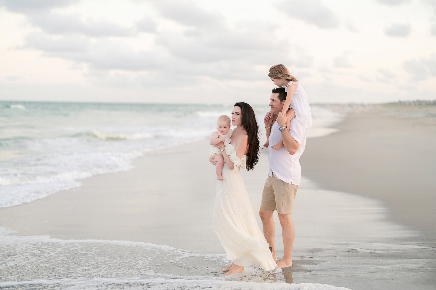 Soft focus of a happy family enjoying beach portraits at sunset with ocean waves in the background.