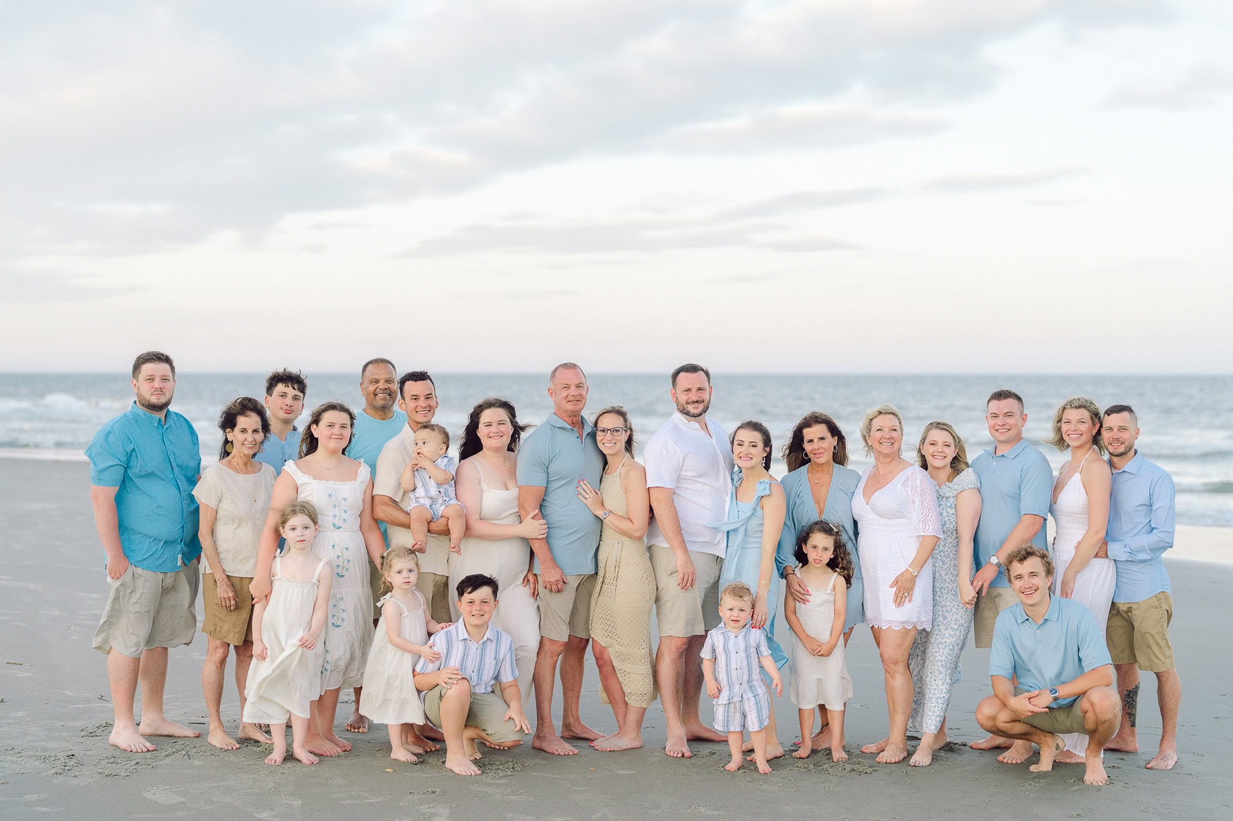 Portrait of a large multi-generational family on the beach, celebrating together with a joyful seaside group photo, perfect for family beach portraits and special summer gatherings.