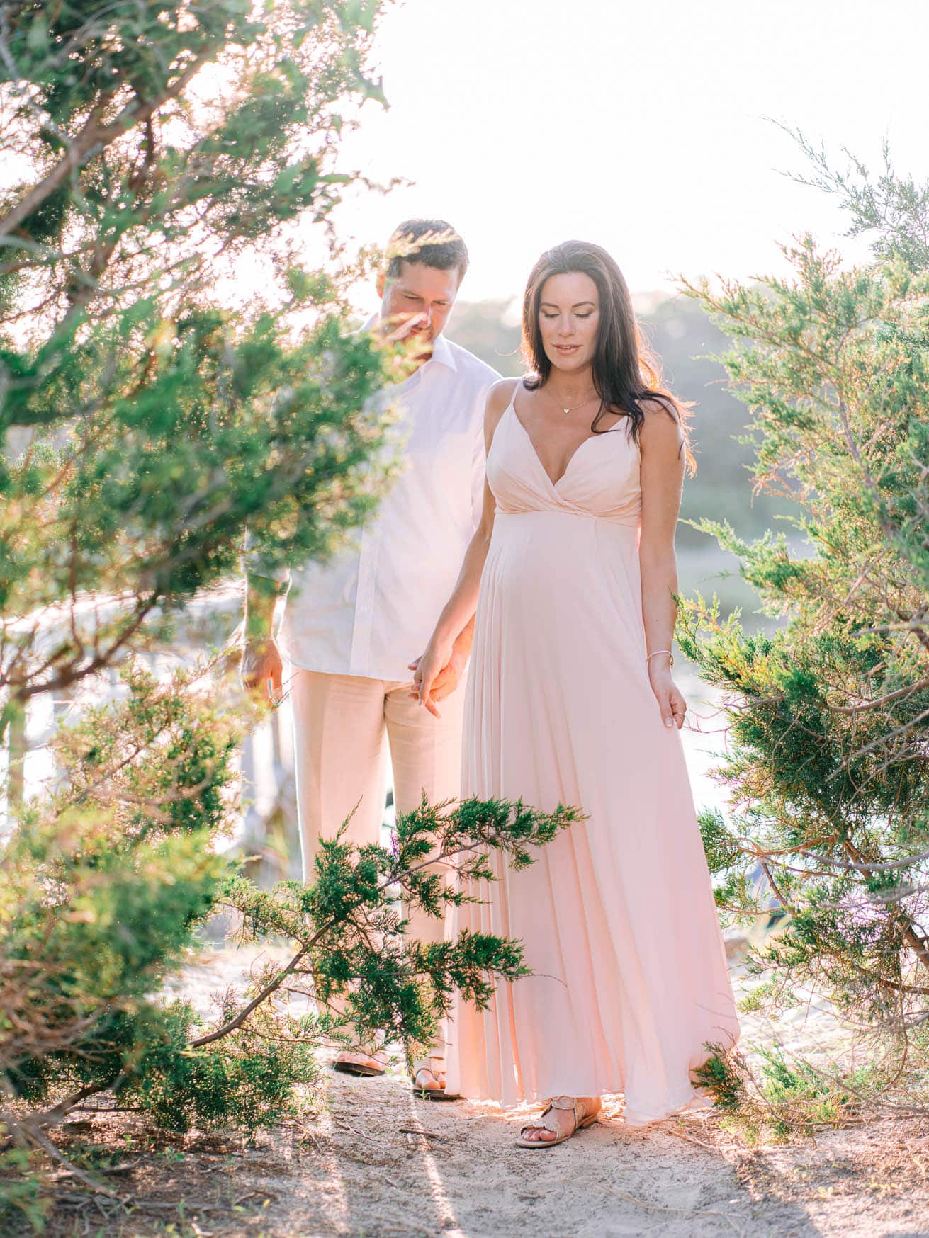 Soft romantic beach wedding photography with a couple holding hands among lush greenery, captured during golden hour, highlighting love and natural scenery.