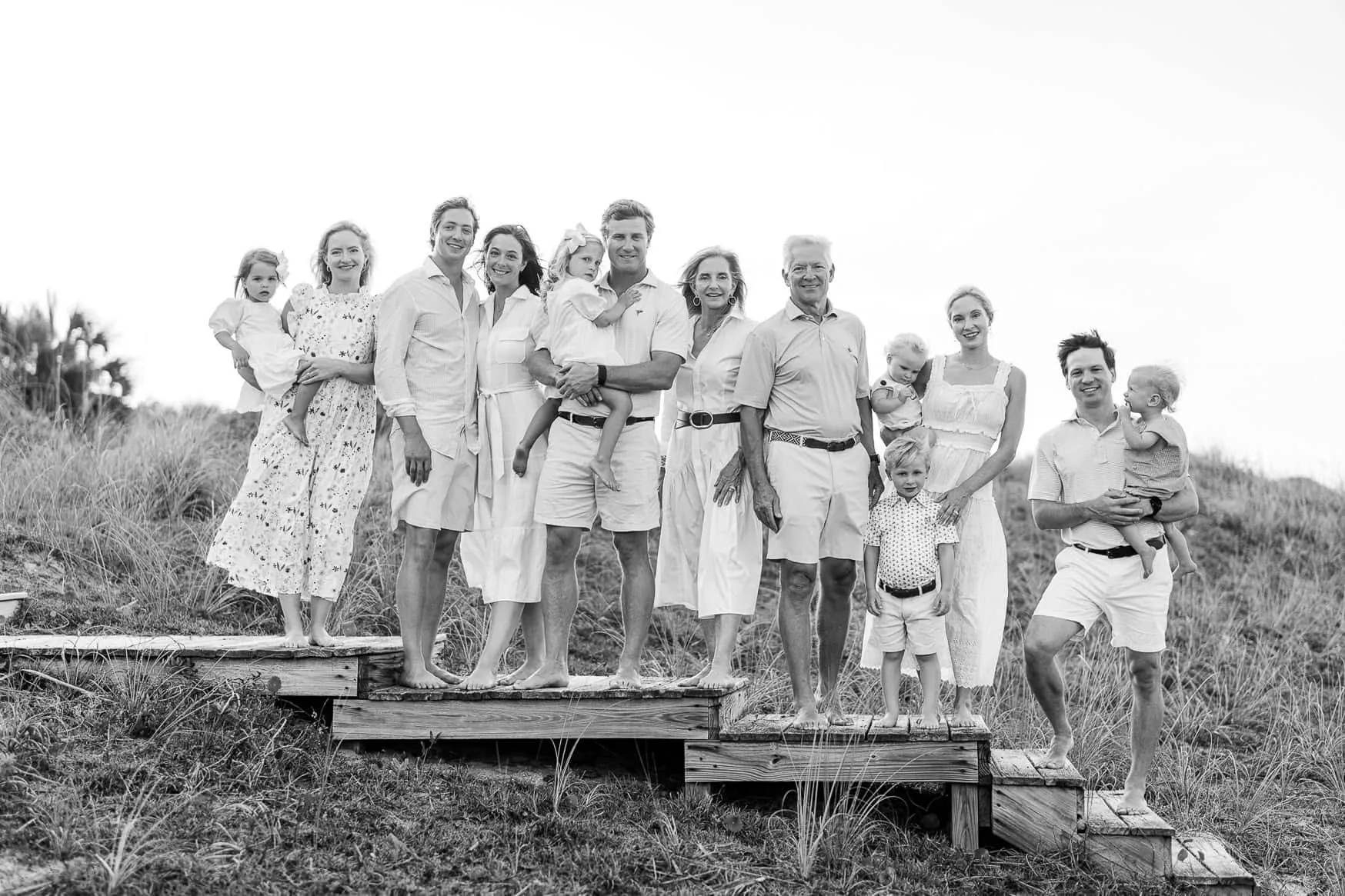 Black and white portrait of a multigenerational family in white standing on a dune boardwalk at Pawleys Island