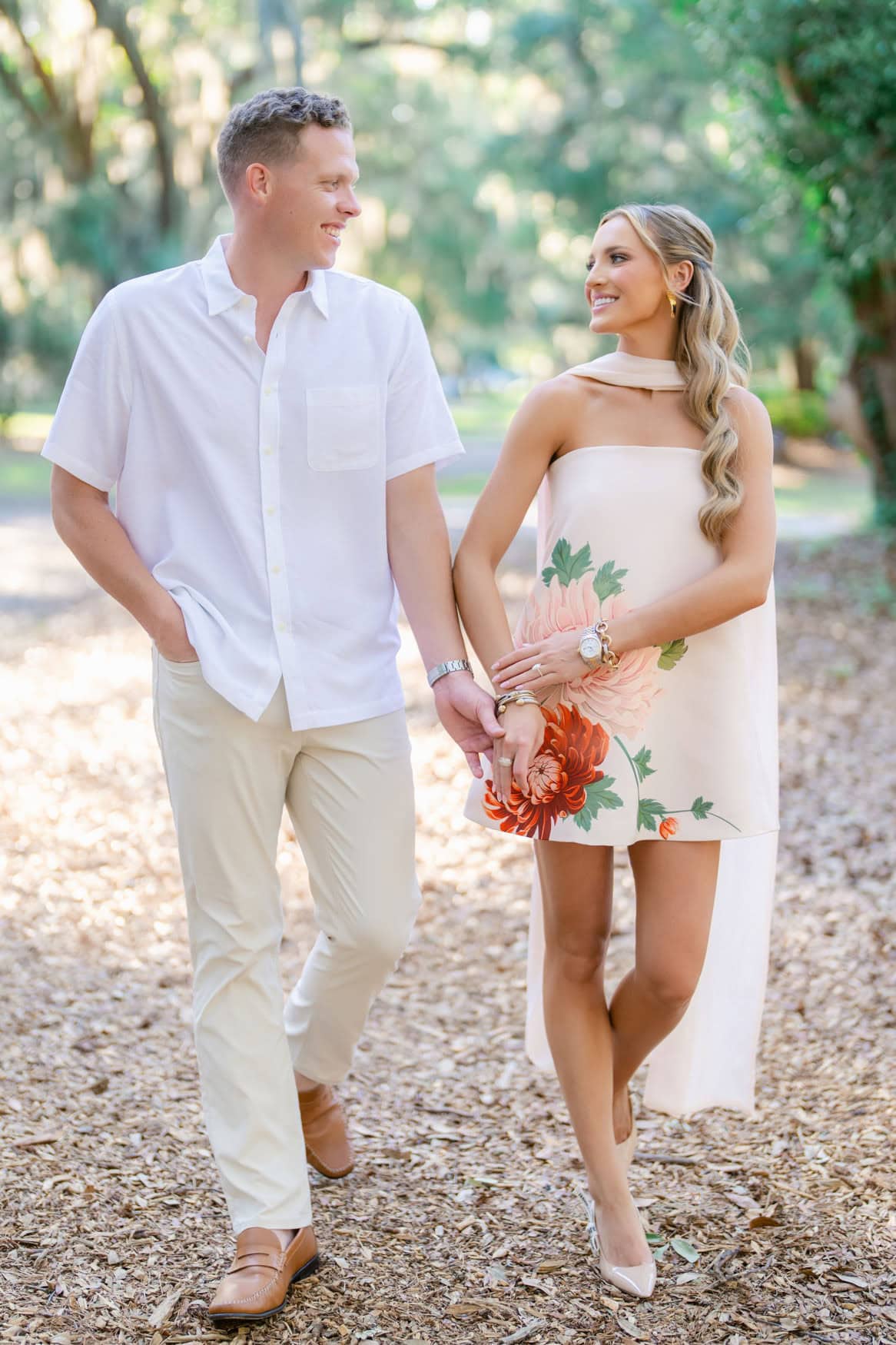 Bride to be in blush floral cape dress standing under a live oak arch during Pawleys Island engagement session