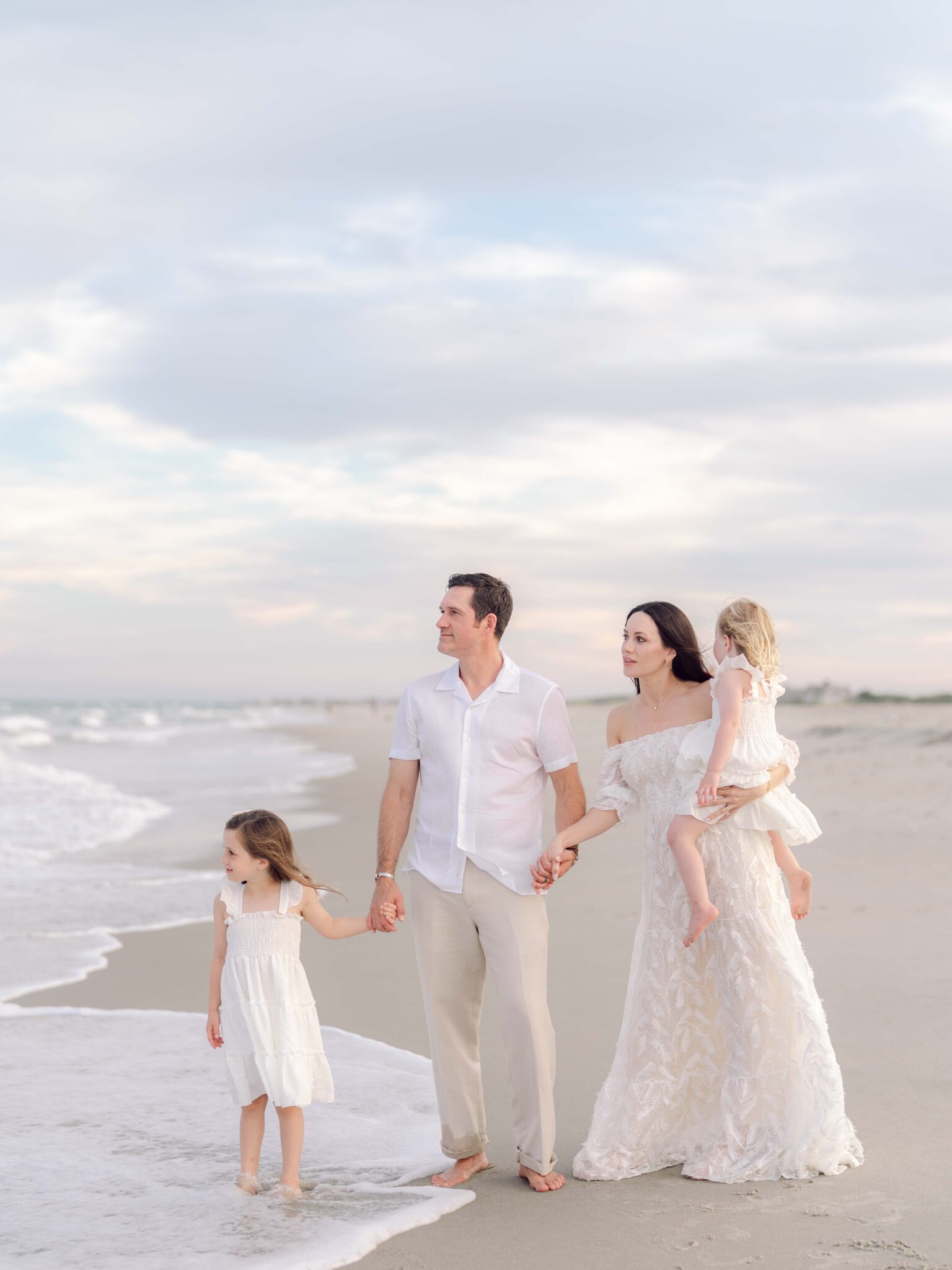 Family of four walking along the shoreline during a Pawleys Island family photography session at sunset.