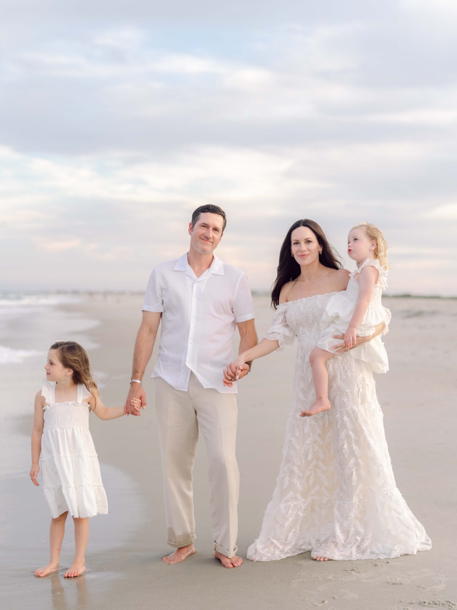 Family walking away together along the shoreline during a Pawleys Island family photography session.