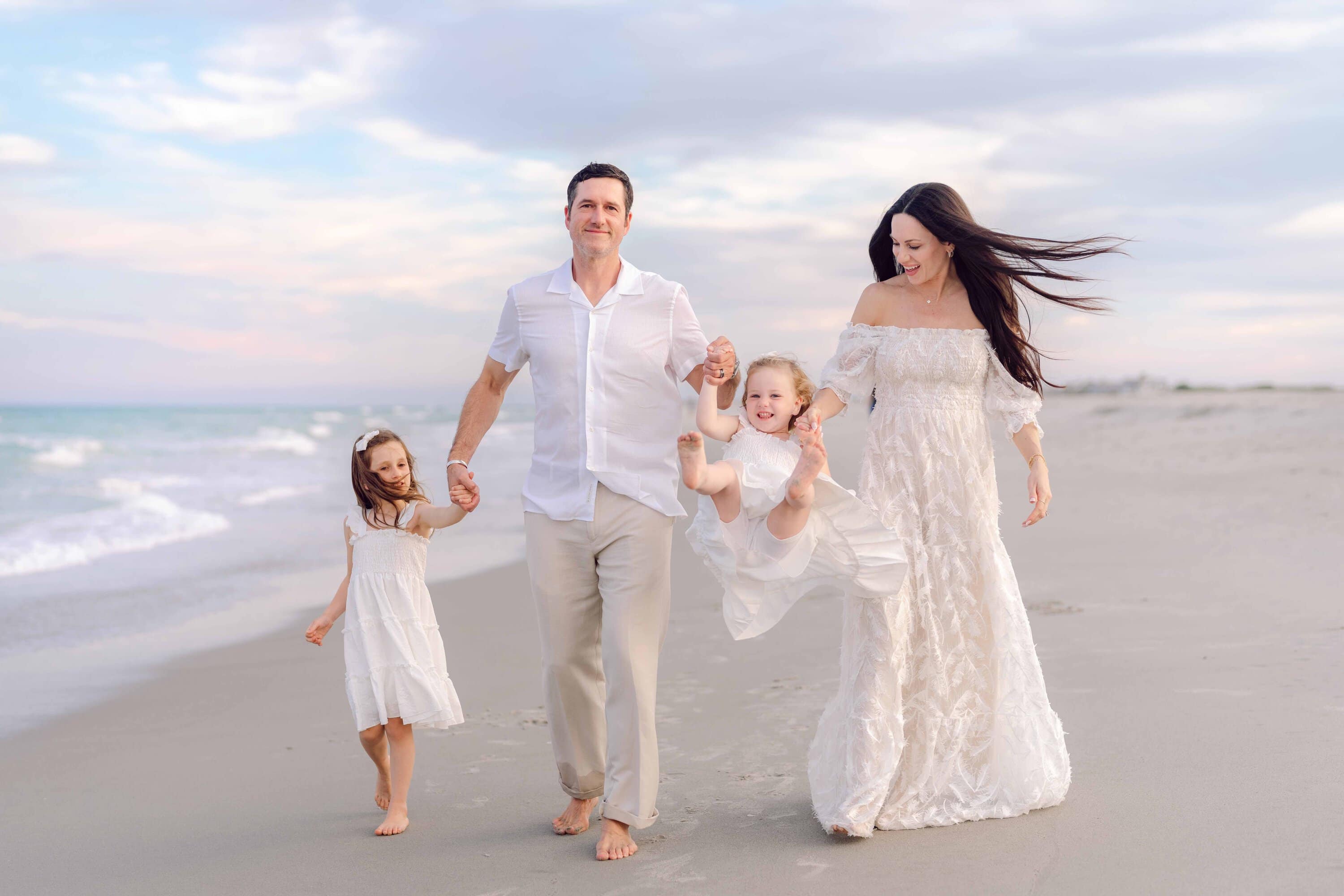 Parents walking with their daughters along the beach in Pawleys Island, South Carolina.