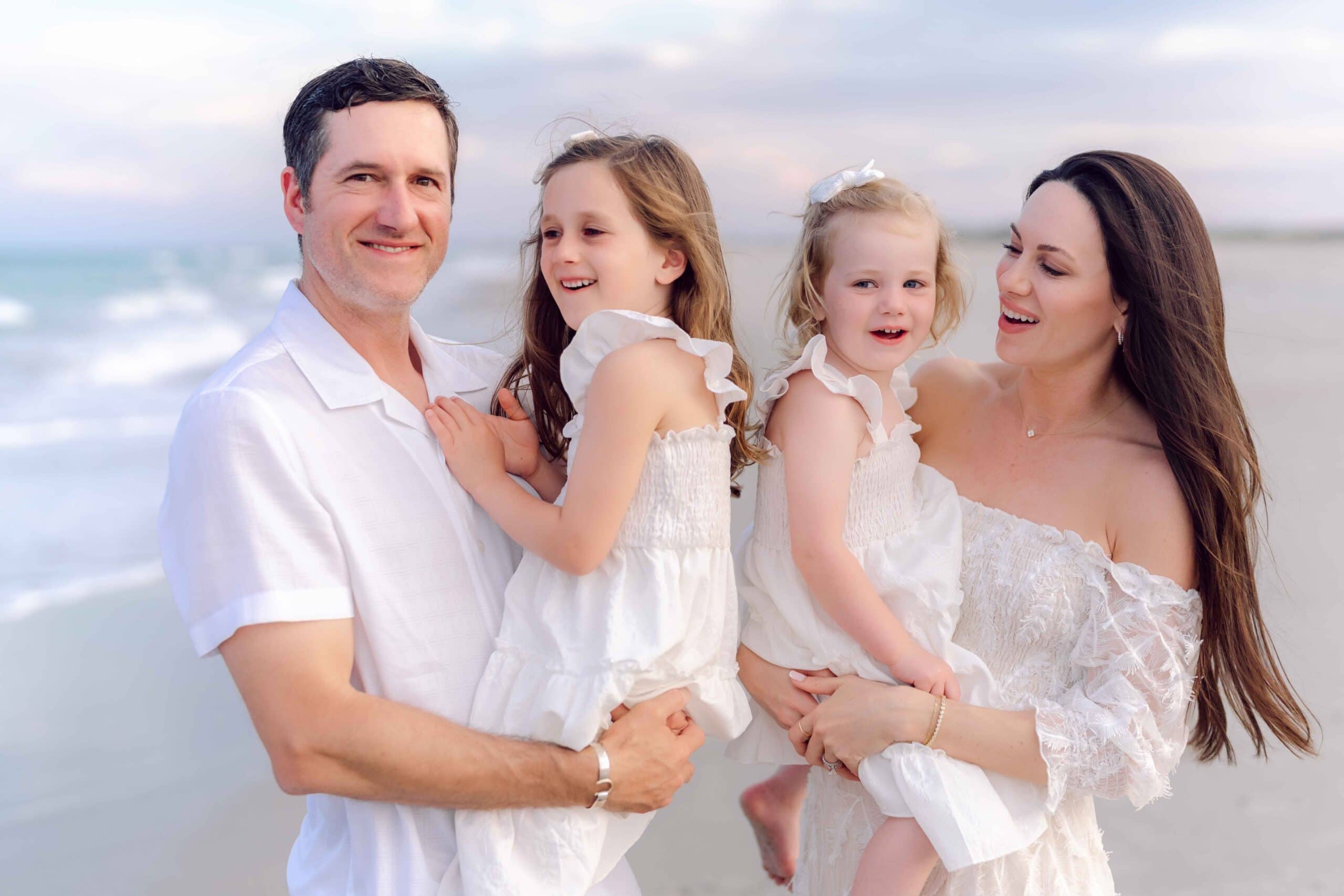 Family of four smiling together during a Pawleys Island beach portrait session.