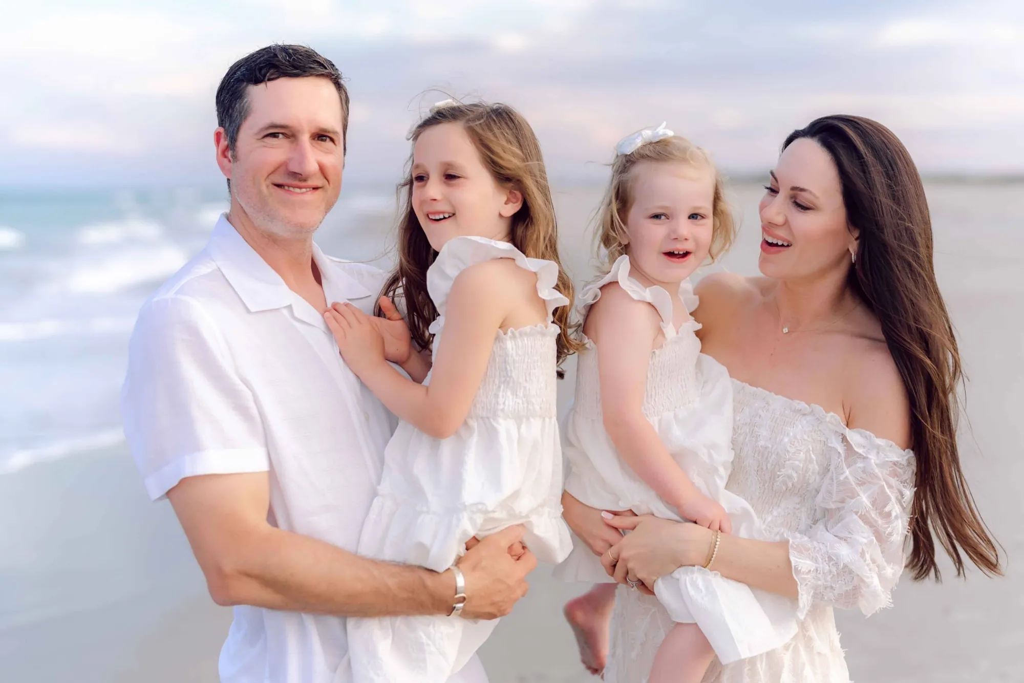 Family of four smiling together during a Pawleys Island beach portrait session.