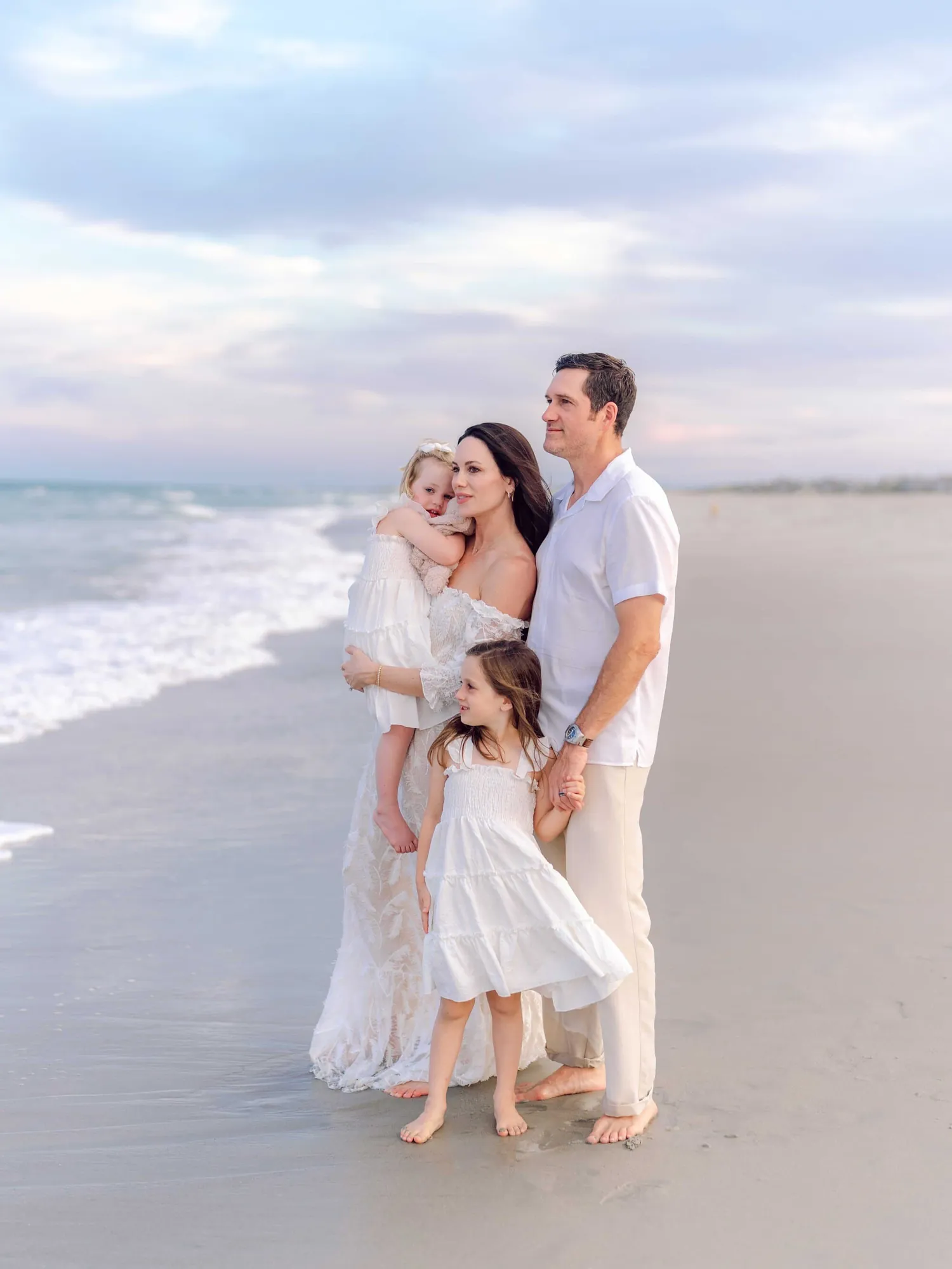 Family wearing coordinated white and neutral outfits for family beach photos in Pawleys Island, South Carolina.