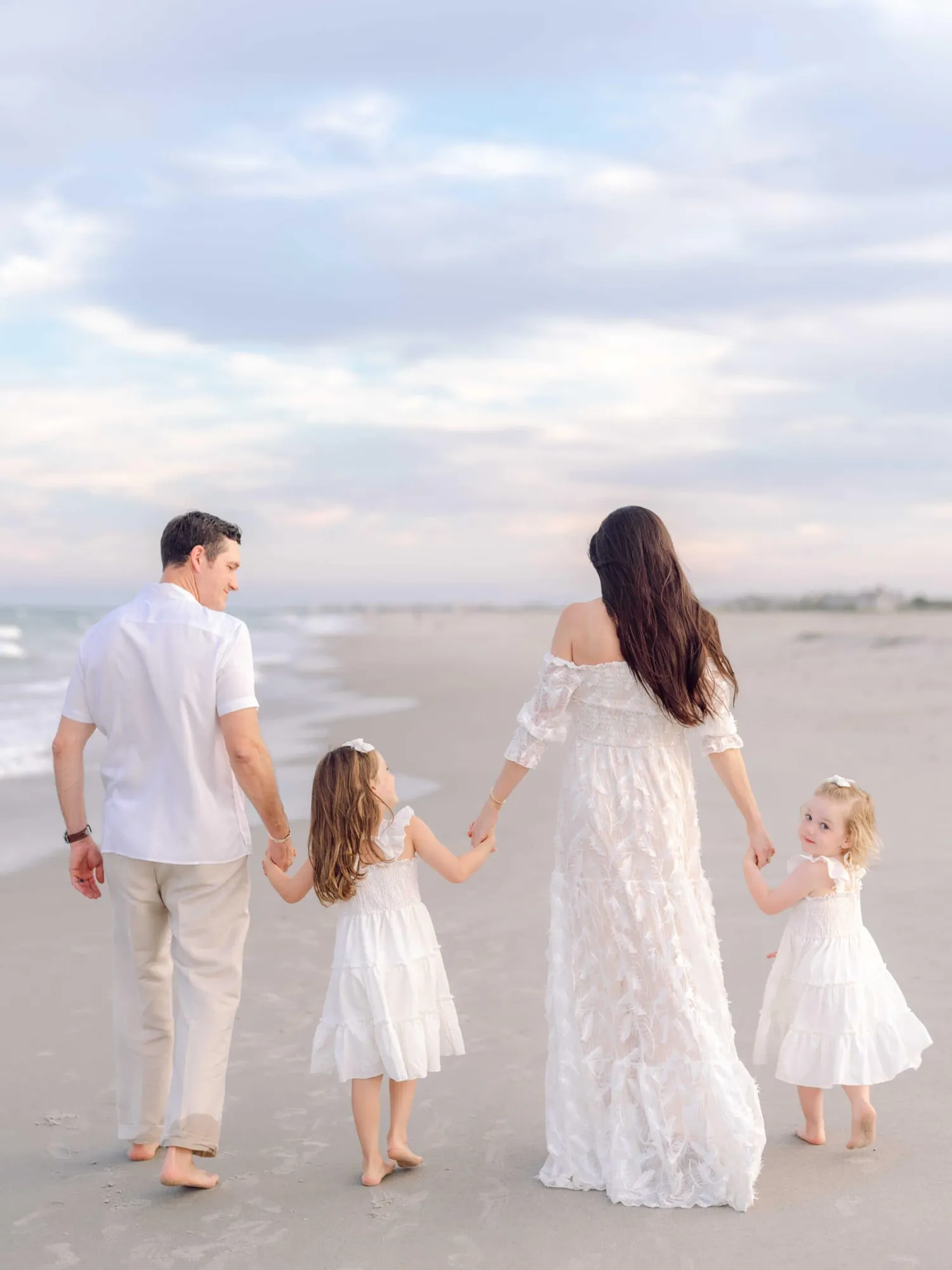 Father carrying his daughters while walking beside their mother on Pawleys Island beach.