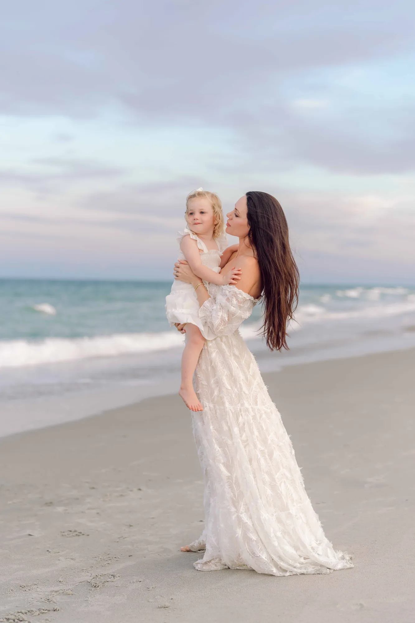 Mother holding her young daughter on the beach during a Pawleys Island family portrait session.