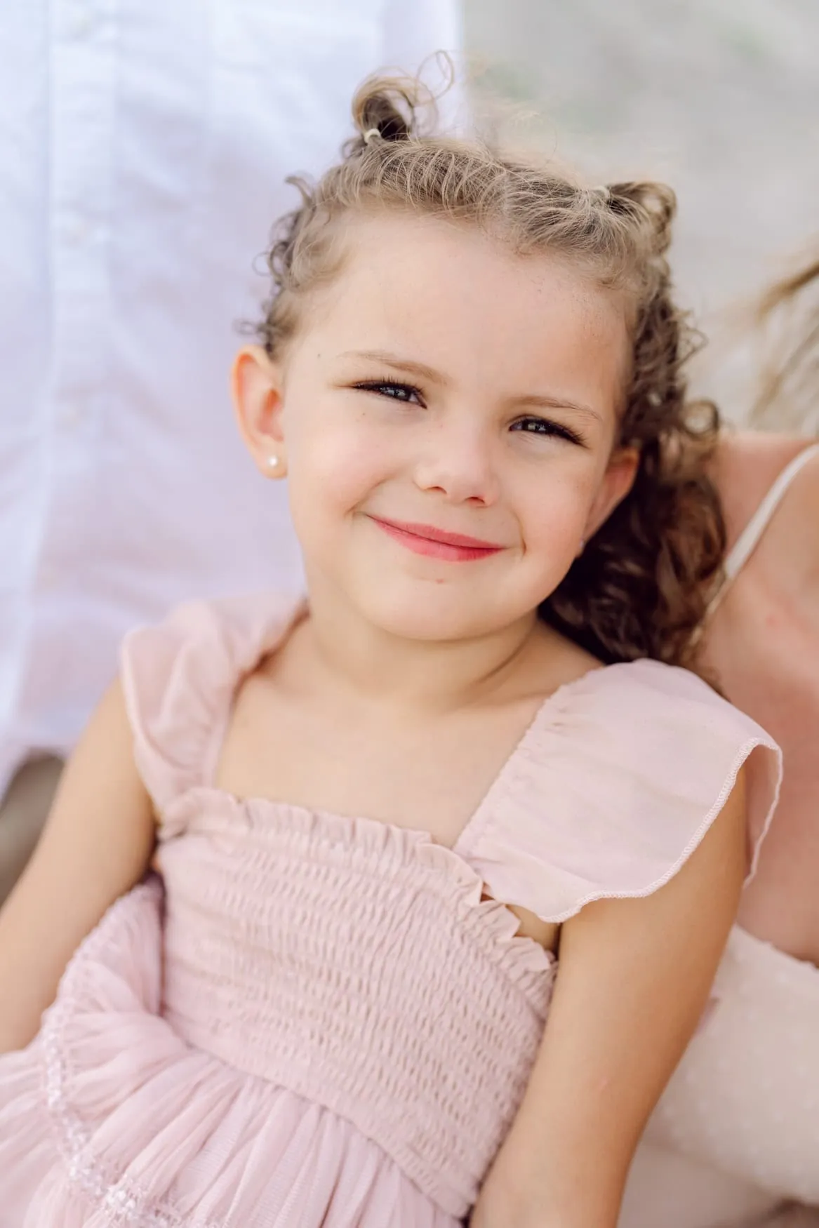 Young girl smiling during a family beach photography session at Wild Dunes Resort in Isle of Palms near Charleston, South Carolina. Natural child portrait captured in soft evening light on the beach.