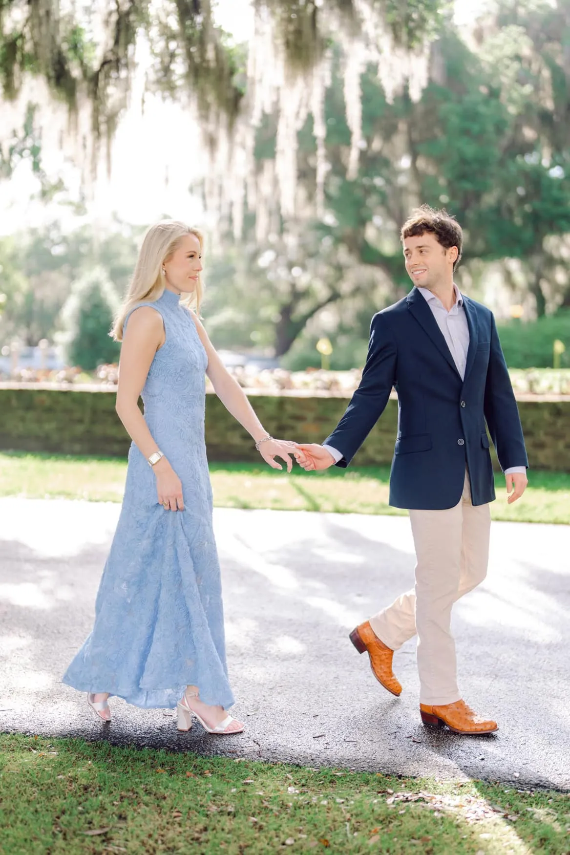 Couple in a long light blue dress and navy blazer beneath Spanish moss in Charleston