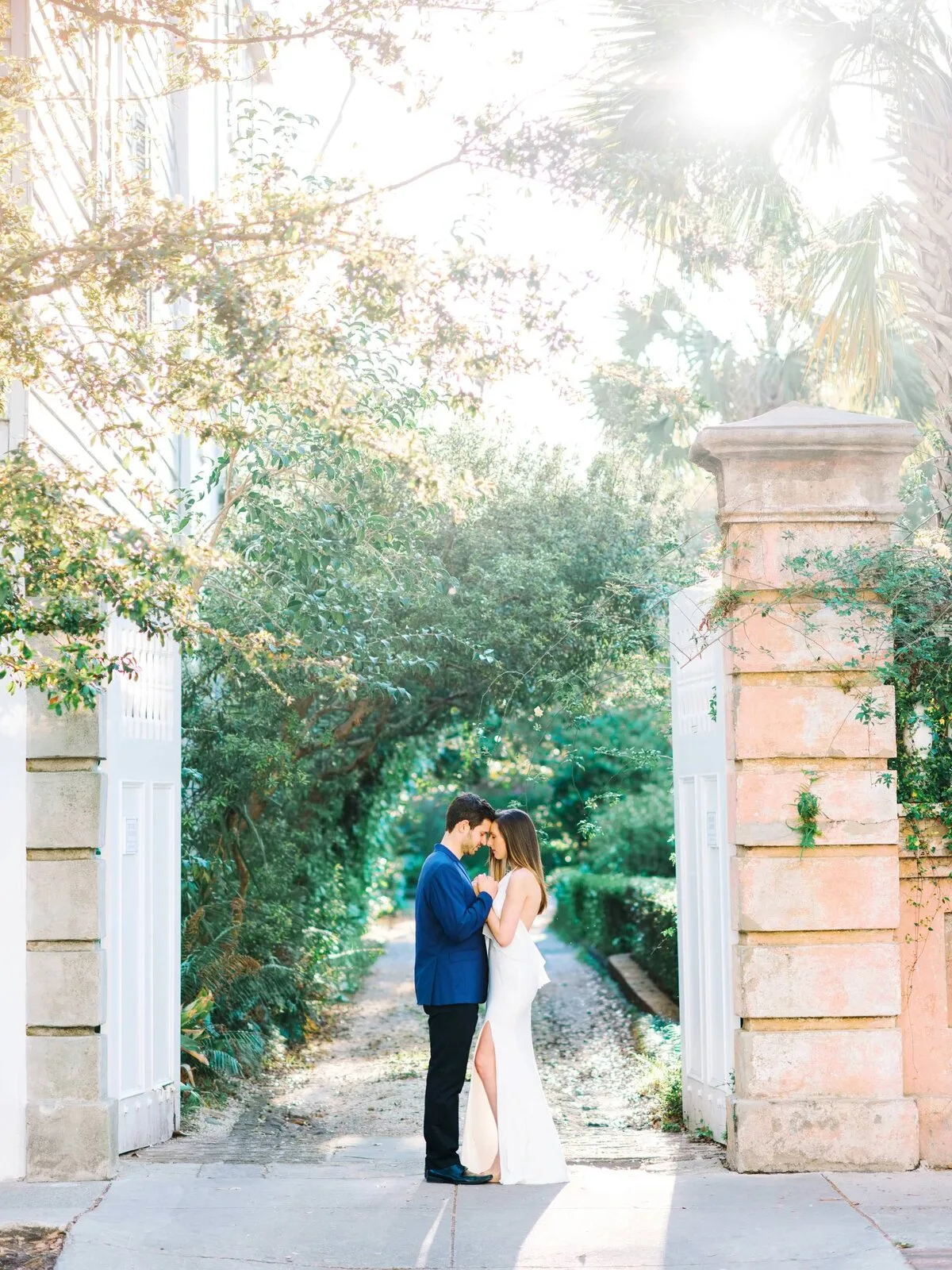 Engaged couple embracing at a brick gate in historic Charleston SC