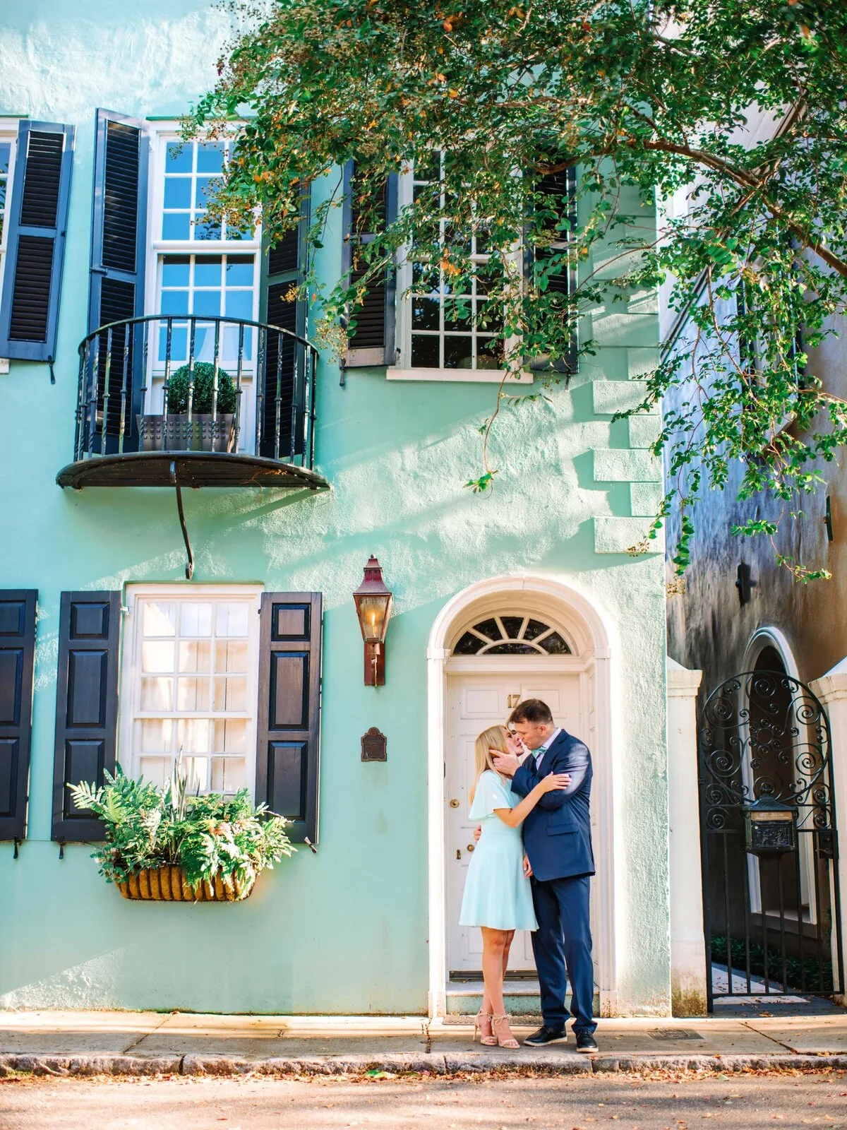 Engaged couple in front of a turquoise house in downtown Charleston SC