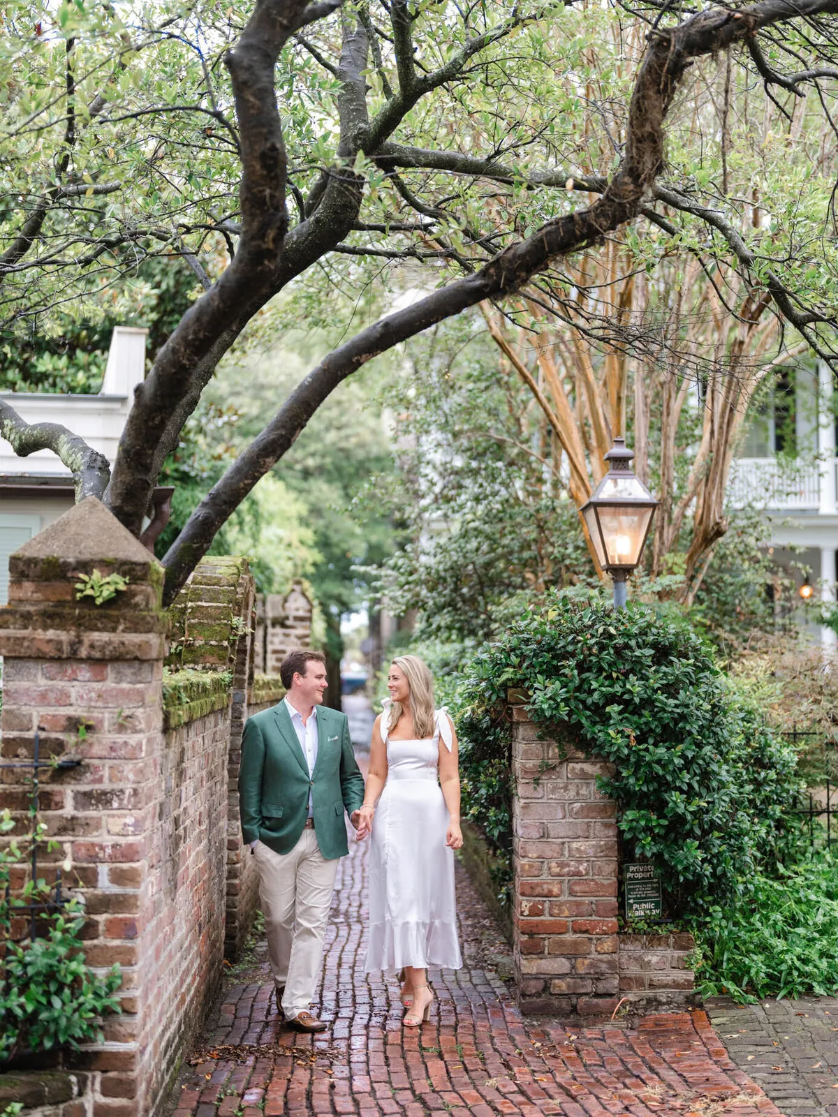 Engaged couple on a brick alley beneath the oaks in Charleston SC