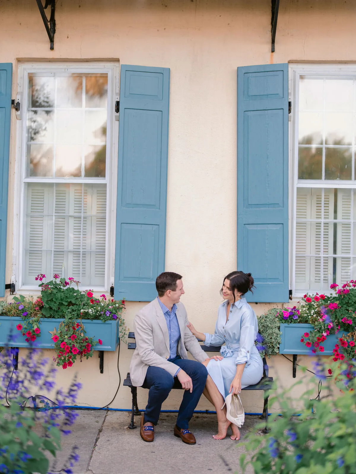 Engaged couple sitting on a bench by flower boxes in Charleston SC