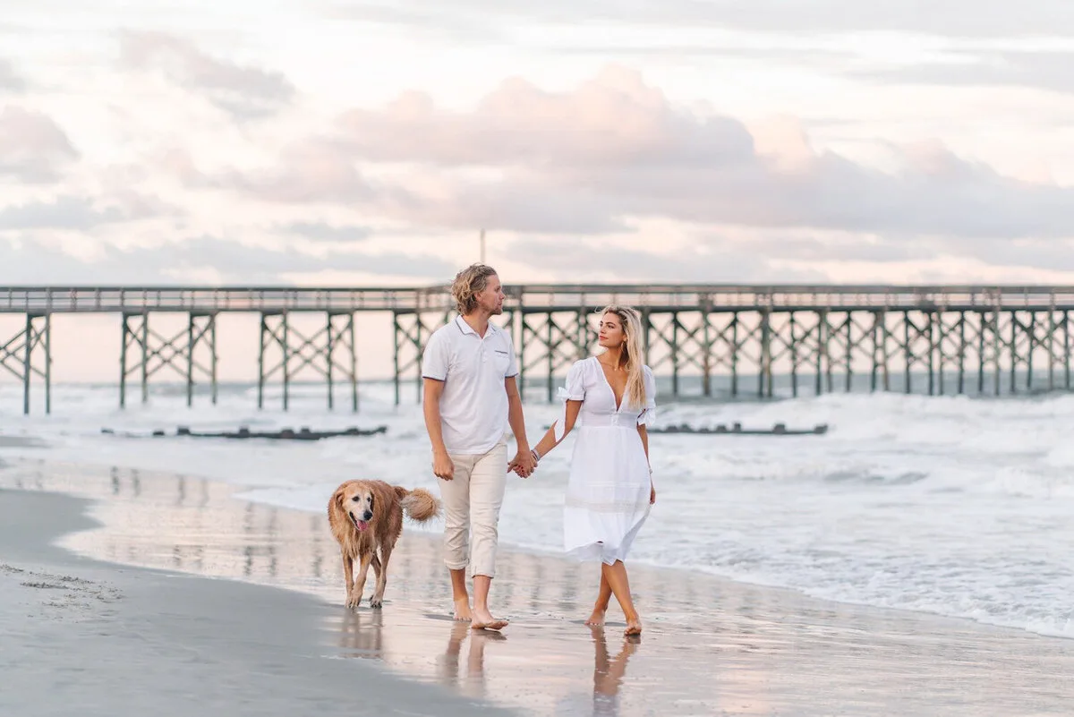 Couple and dog walking by the pier near Charleston SC
