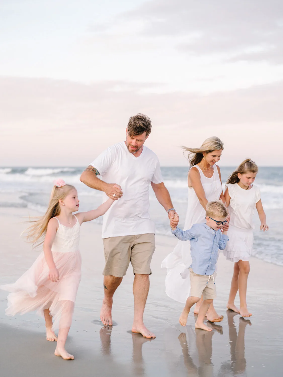 Family walking the shoreline at sunset near Charleston SC