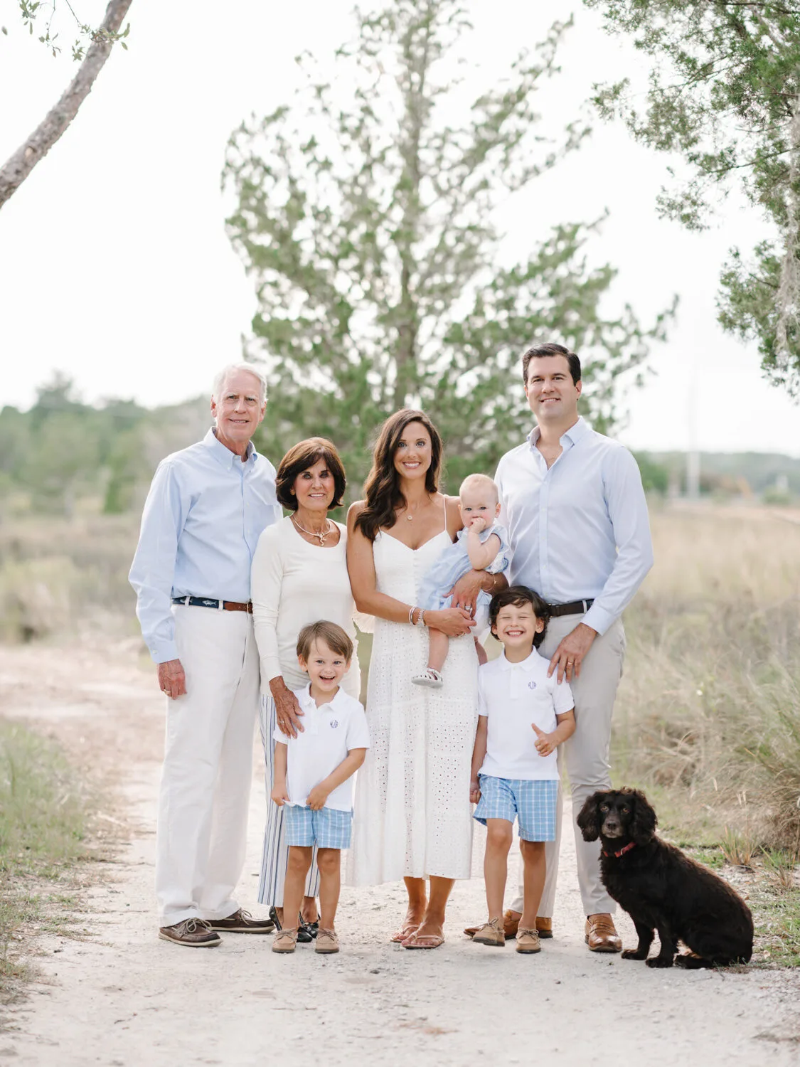 Multigenerational family with a black dog on a dune path near Charleston SC