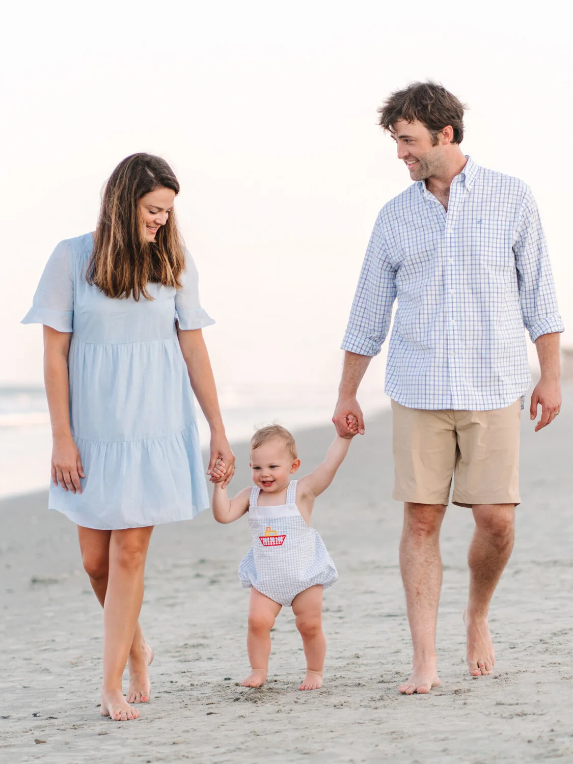 Parents holding their toddler's hands on the sand near Charleston SC