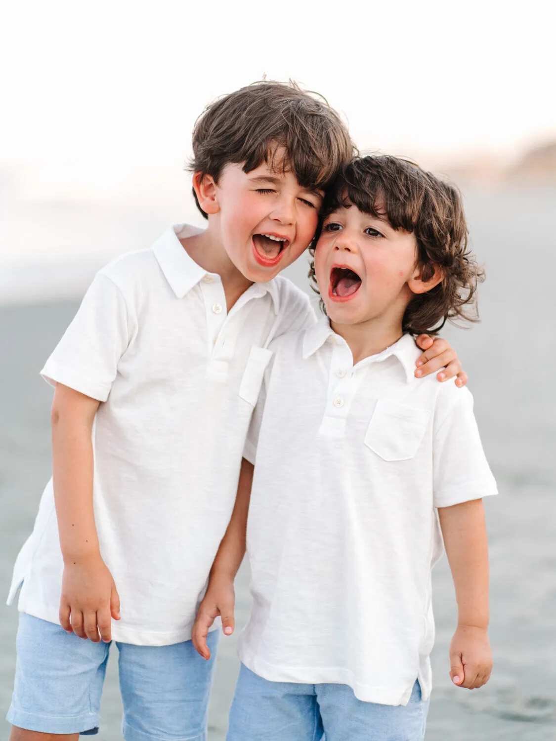 Two brothers laughing in white shirts on the beach near Charleston SC