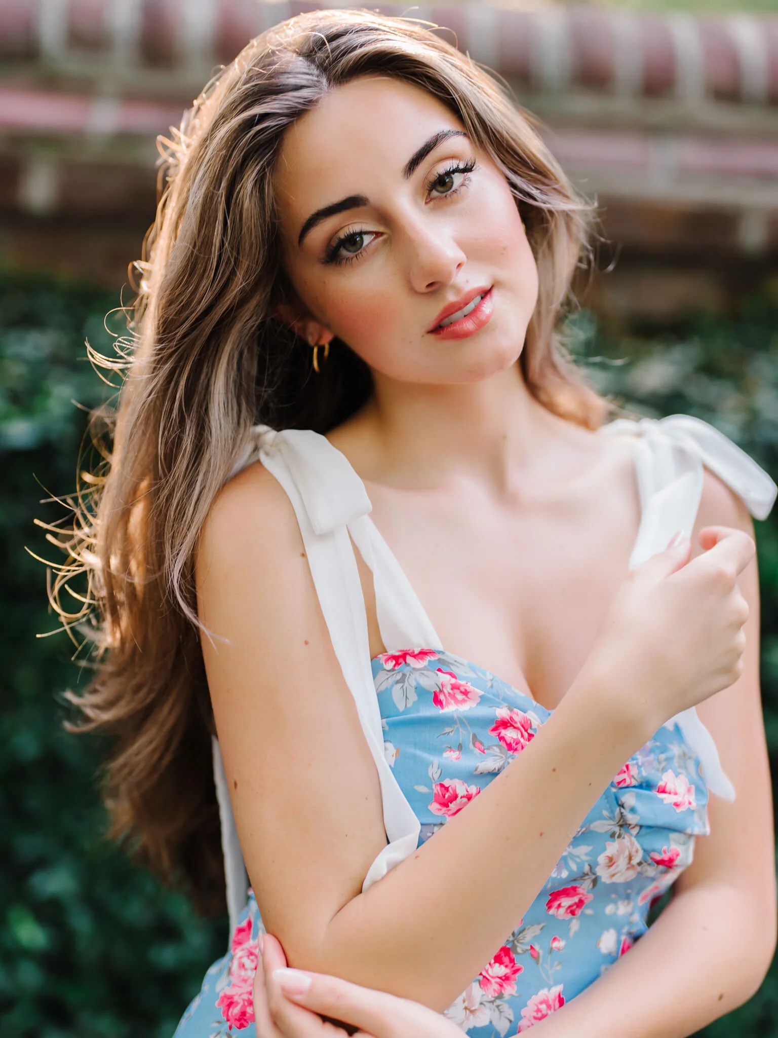 Close-up portrait of a Charleston senior girl in a blue floral dress with white tie straps and long brown hair