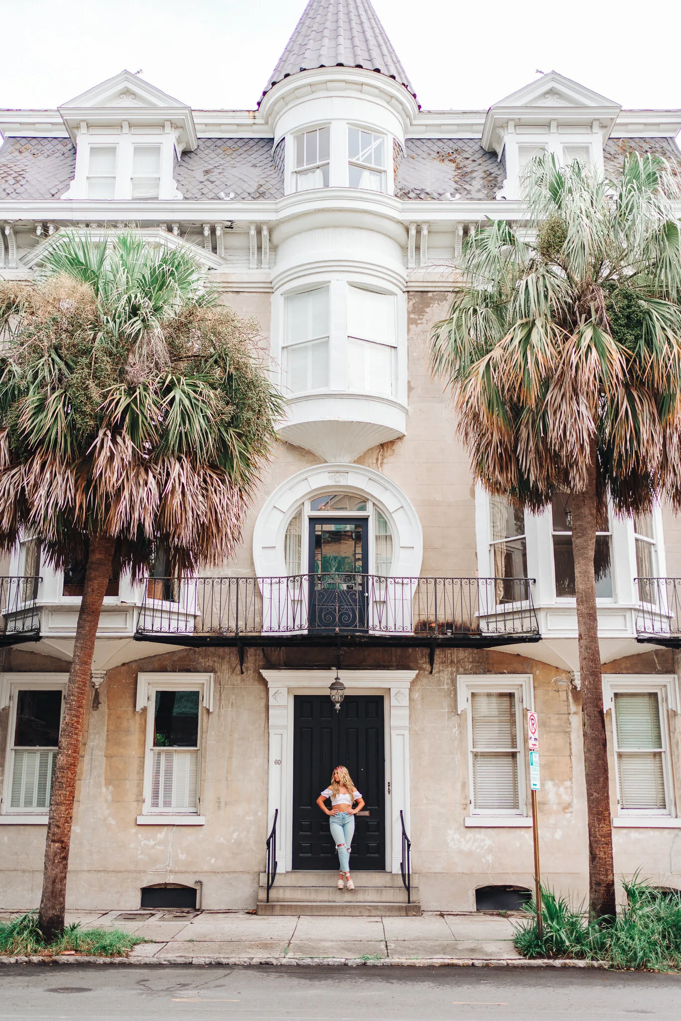 Senior girl standing at the front door of a historic downtown Charleston mansion framed by palmetto palms