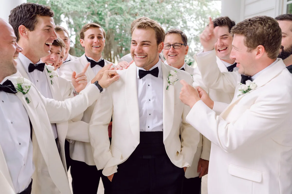 Groomsmen laughing in white dinner jackets at a Charleston SC wedding