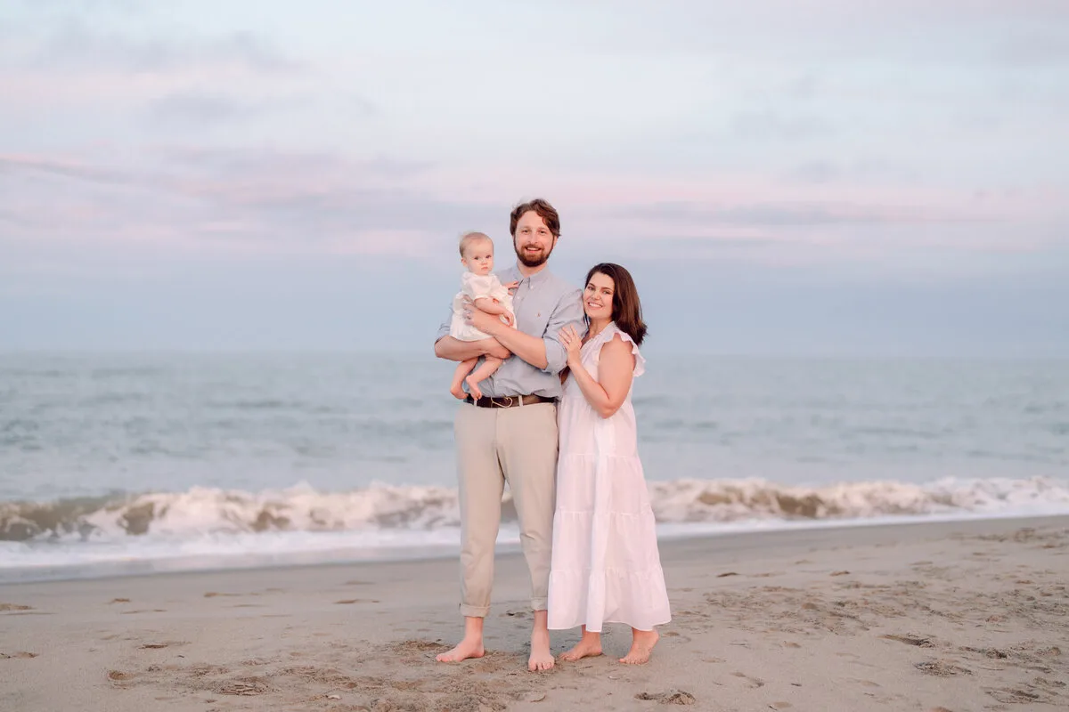Couple with their child at the shoreline at dusk at DeBordieu Beach