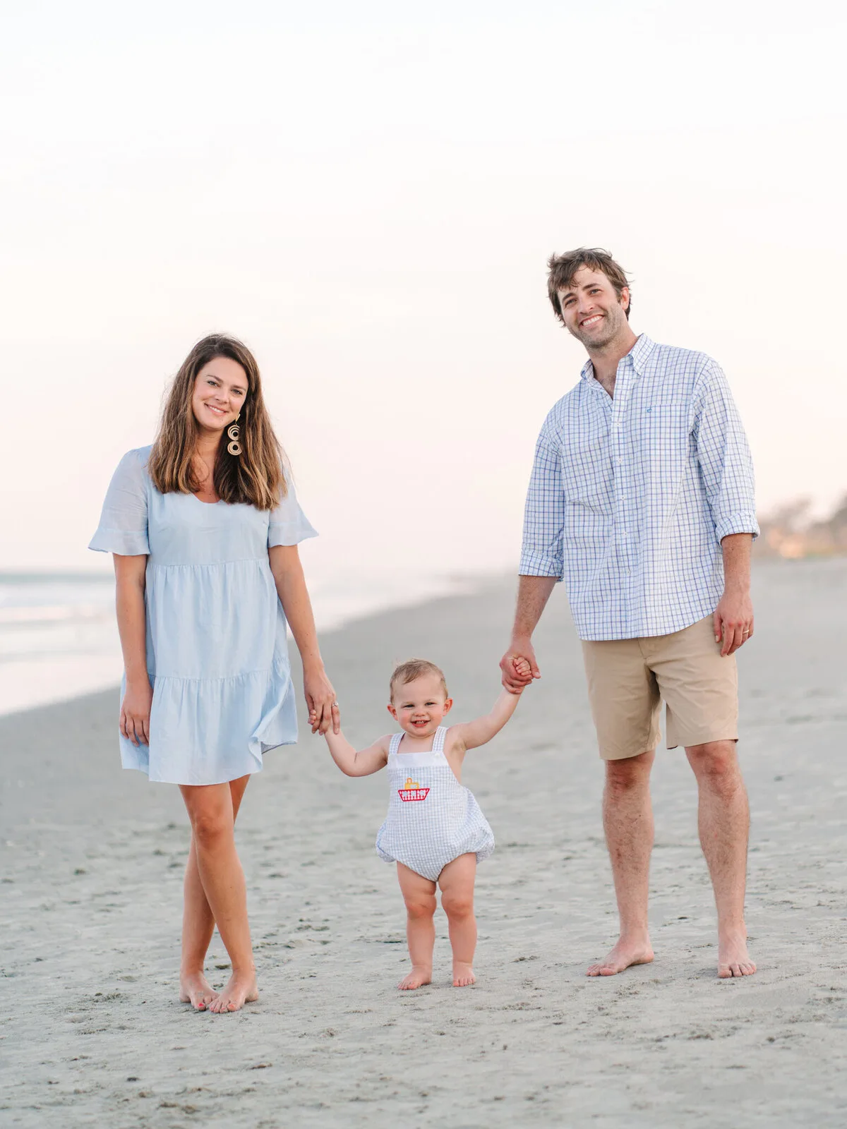 Parents walking with their toddler on the sand at DeBordieu Beach