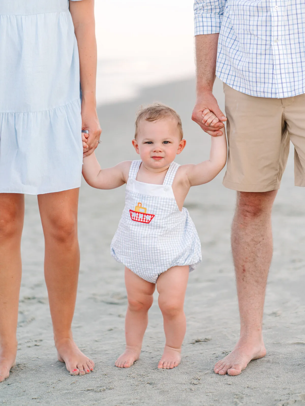 Toddler walking between his parents on DeBordieu Beach