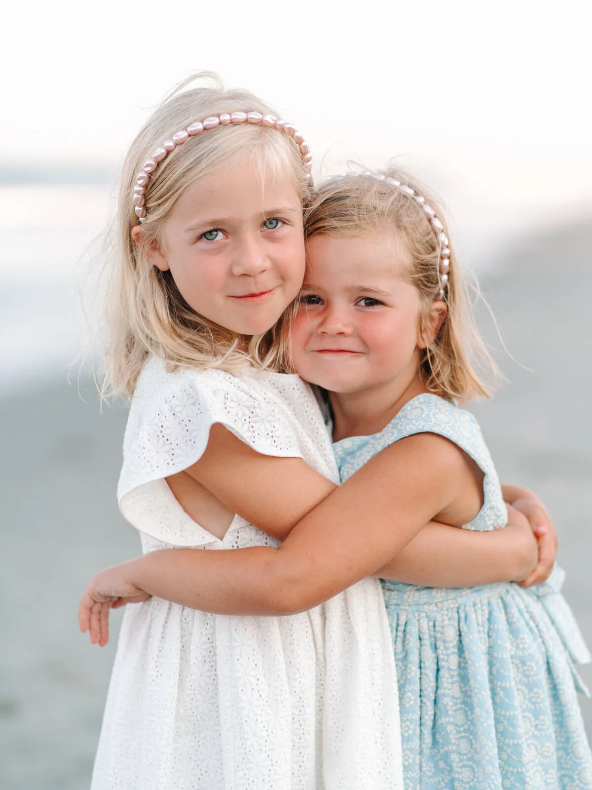 Two sisters hugging in pearl headbands on DeBordieu Beach