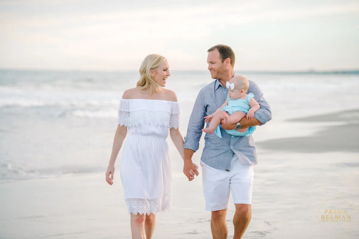 Couple walking the beach holding their baby in Garden City Beach SC