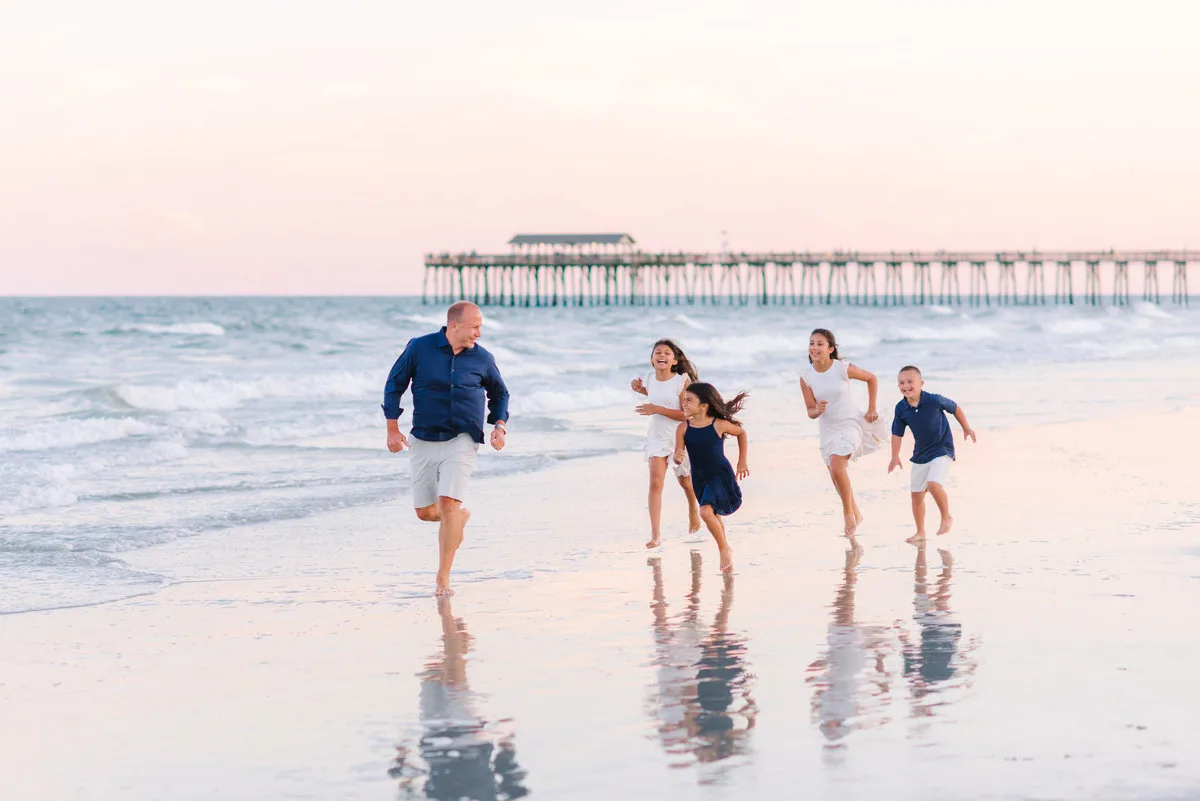 Family walking at the shoreline by the pier in Garden City Beach SC