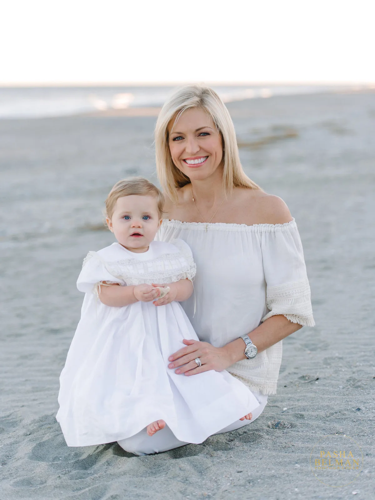 Mother and baby girl sitting on the sand in Garden City Beach SC